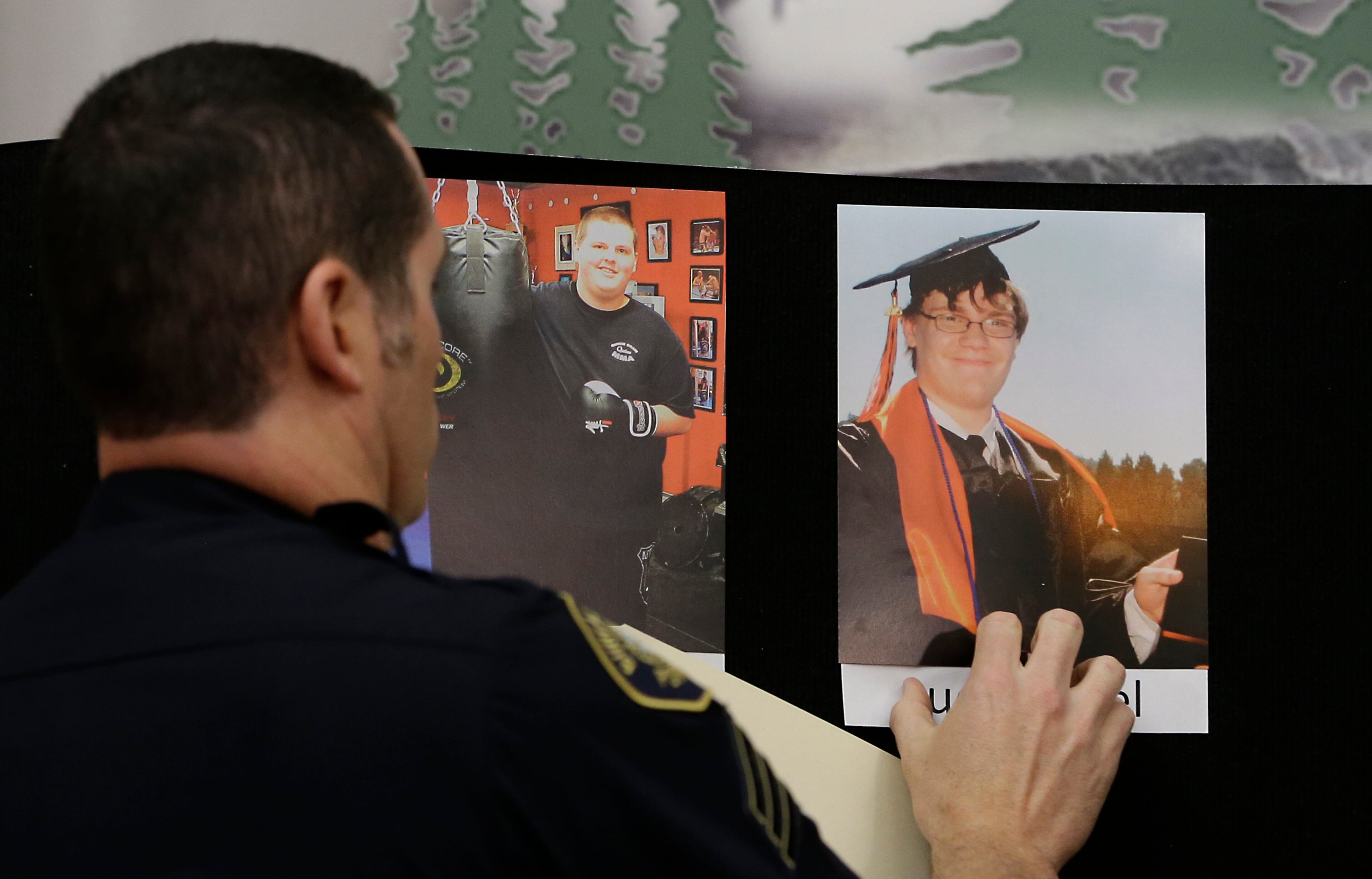 Portland Police Sgt. Pete Simpson places a photo of shooting victim Lucas Eibel, 18, next to a photo of victim Quinn Cooper, 18, for during a news conference, Friday, Oct. 2, 2015, in Roseburg, Ore. Cooper, and Eibel, were among those killed when Chris Harper Mercer, walked into a classroom at the Umpqua Community College the day before and opened fire.(AP Photo/Rich Pedroncelli