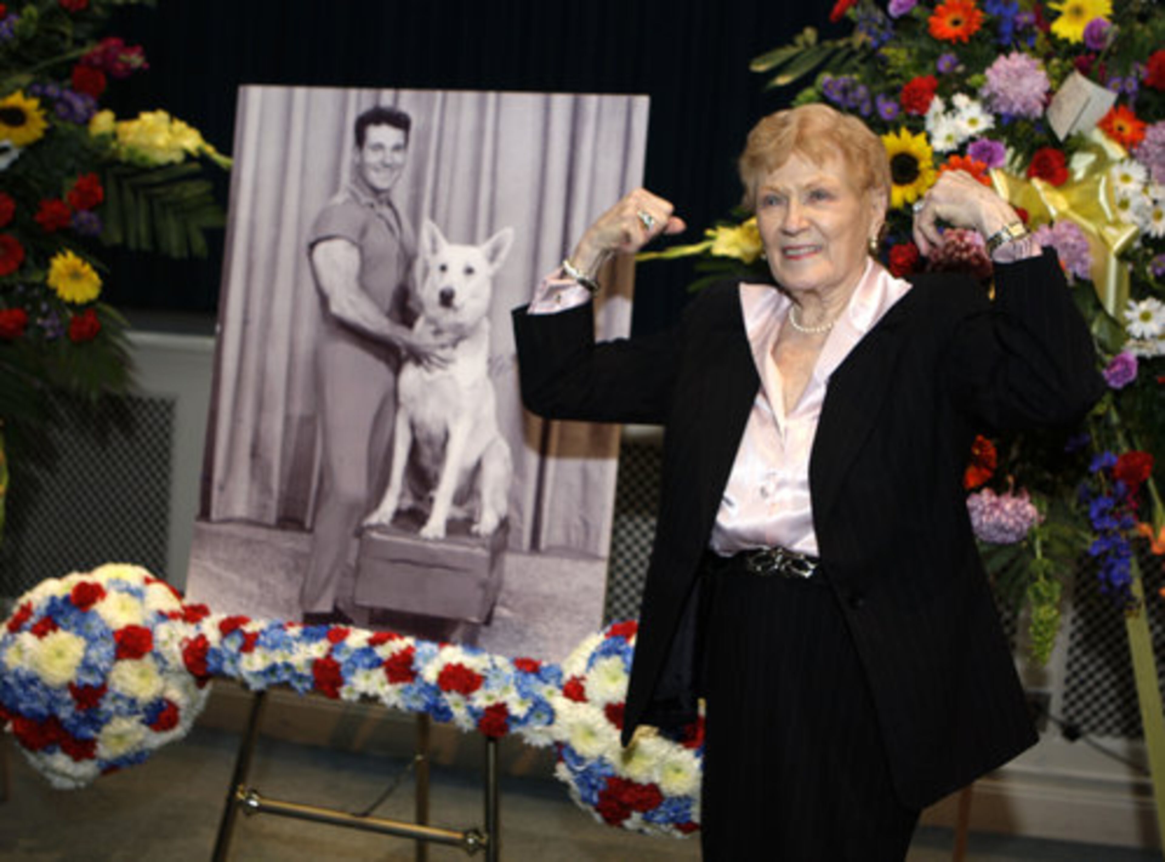 DOING CRUNCHES IN HEAVEN: Elaine LaLannne strikes a characteristic pose near a portrait of her late husband Jack LaLanne at a memorial service for the guru of physical fitness in Los Angeles Tuesday, Feb. 1, 2011. LaLanne died Jan. 23 at the age of 96.