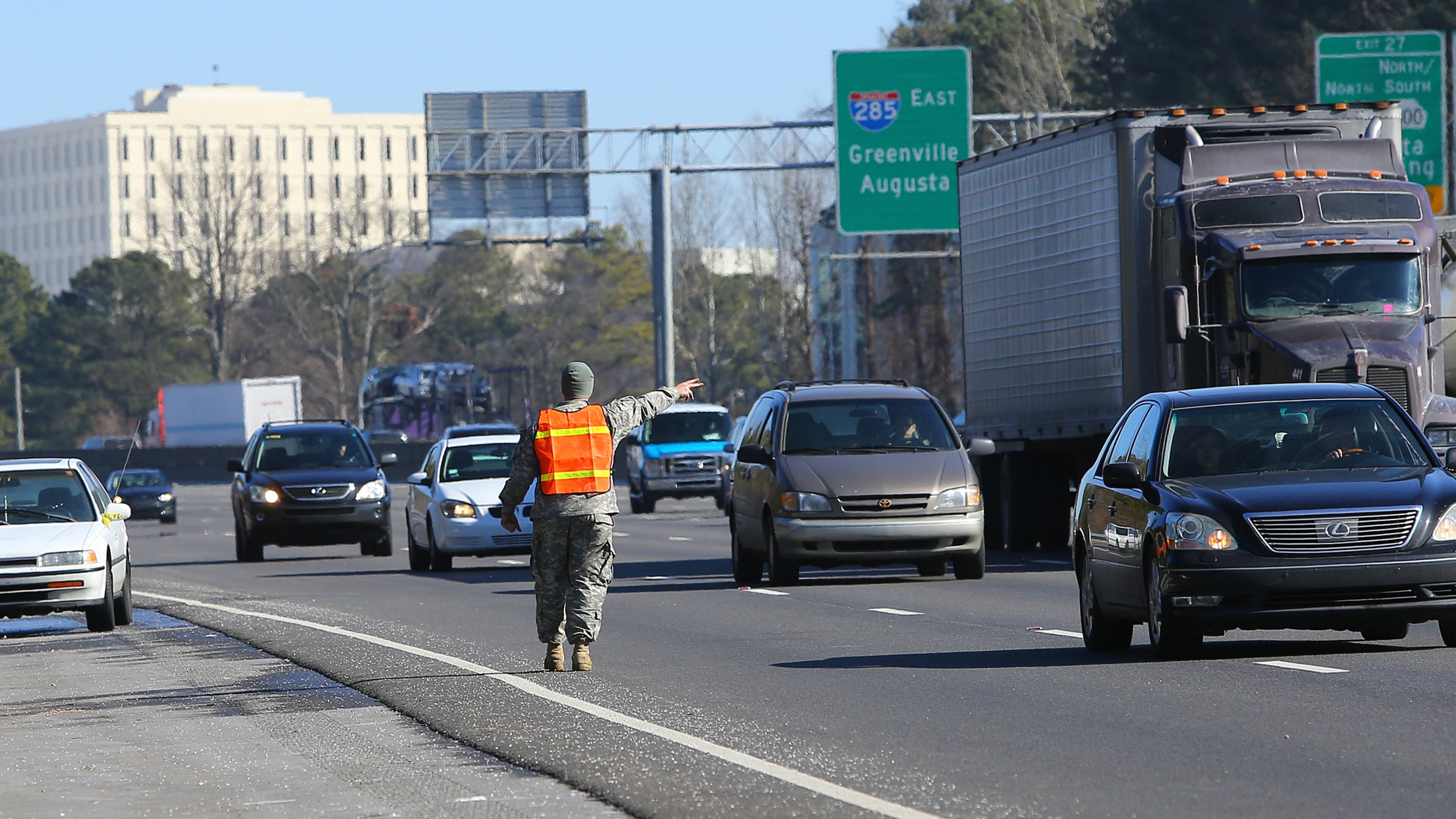 Georgia National Guard staff Sgt. Jared Callaway directs traffic away from the emergency lane while helping Ebony Thomas, of Atlanta, get her car started and back on the road after giving her a ride from the Mount Paran Baptist Church staging area to I-285 near Roswell Road on Thursday, Jan. 30, 2014, in Atlanta. Thomas said she abandoned her vehicle Tuesday afternoon and has been sleeping in the hallway of the nearby Comfort Inn.