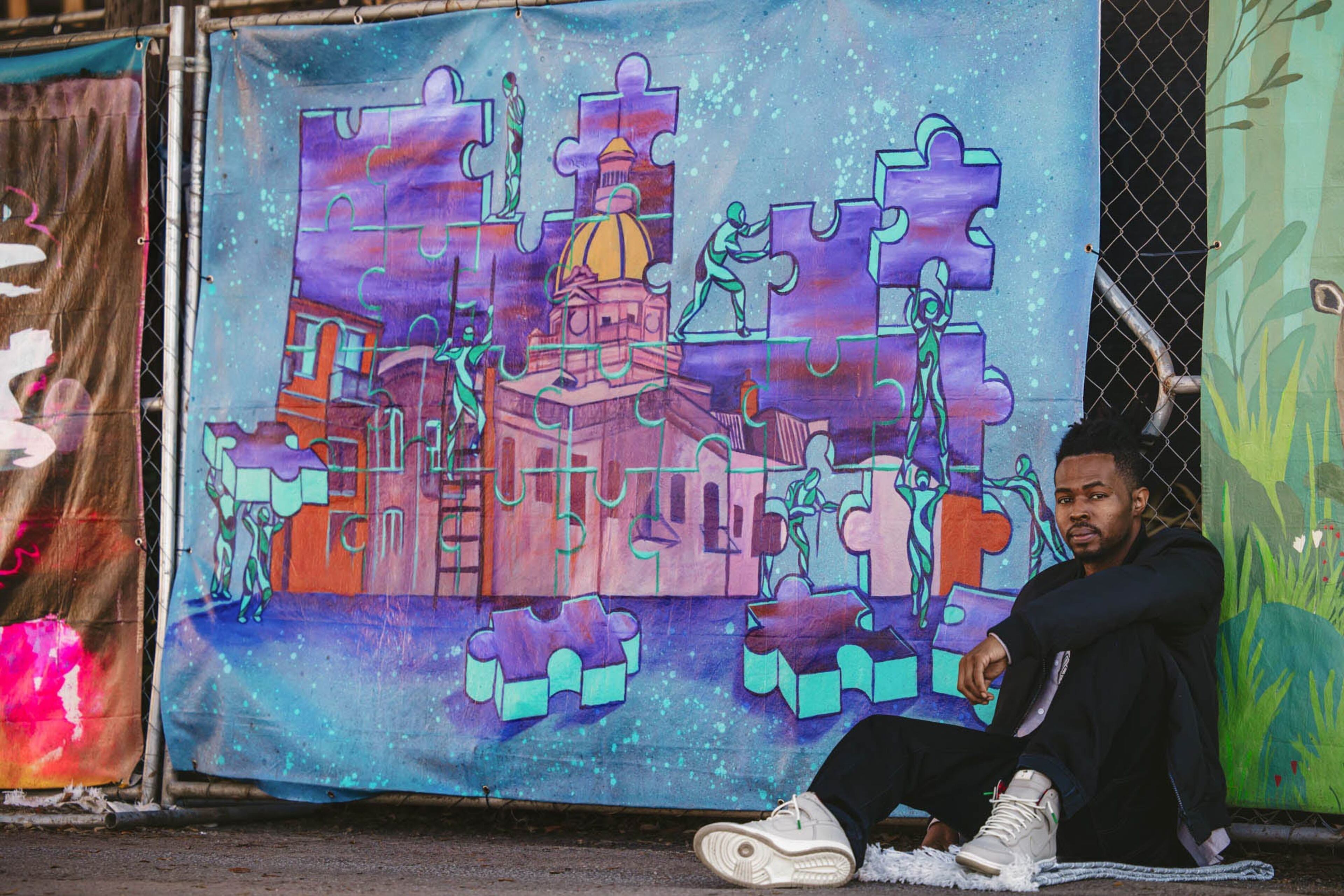 Artist Xavier Hutchins with his canvas on the construction fencing on Bull near 31st Street. (Richard Burkhart / Savannah Morning News)