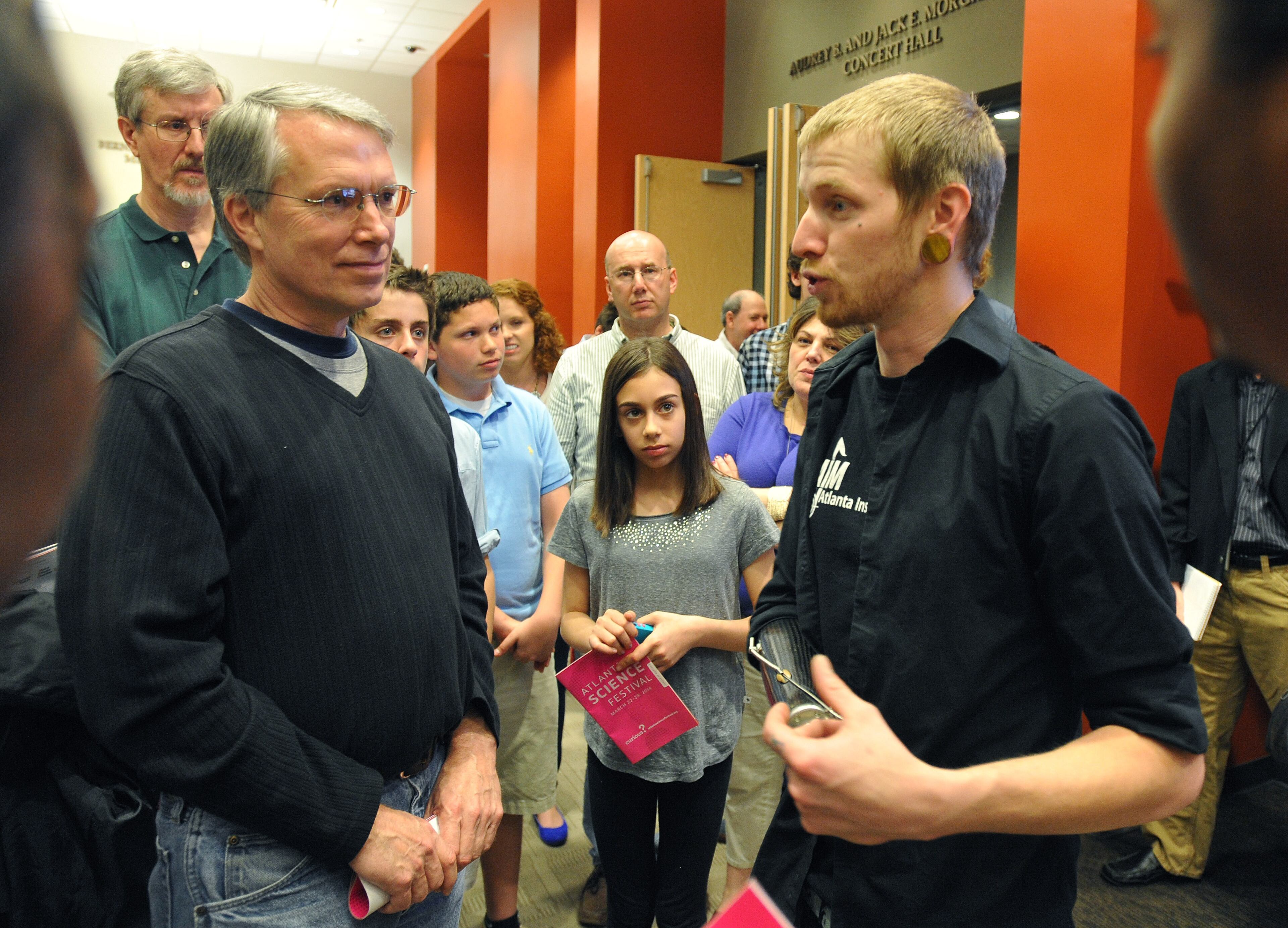 Musician Jason Barnes, right, draws a crowd after performing with his myo-electrically controlled robot arm at a Kennesaw State University concert on Saturday March 21, 2014 in Kennesaw, Ga. David Tulis / AJC Special