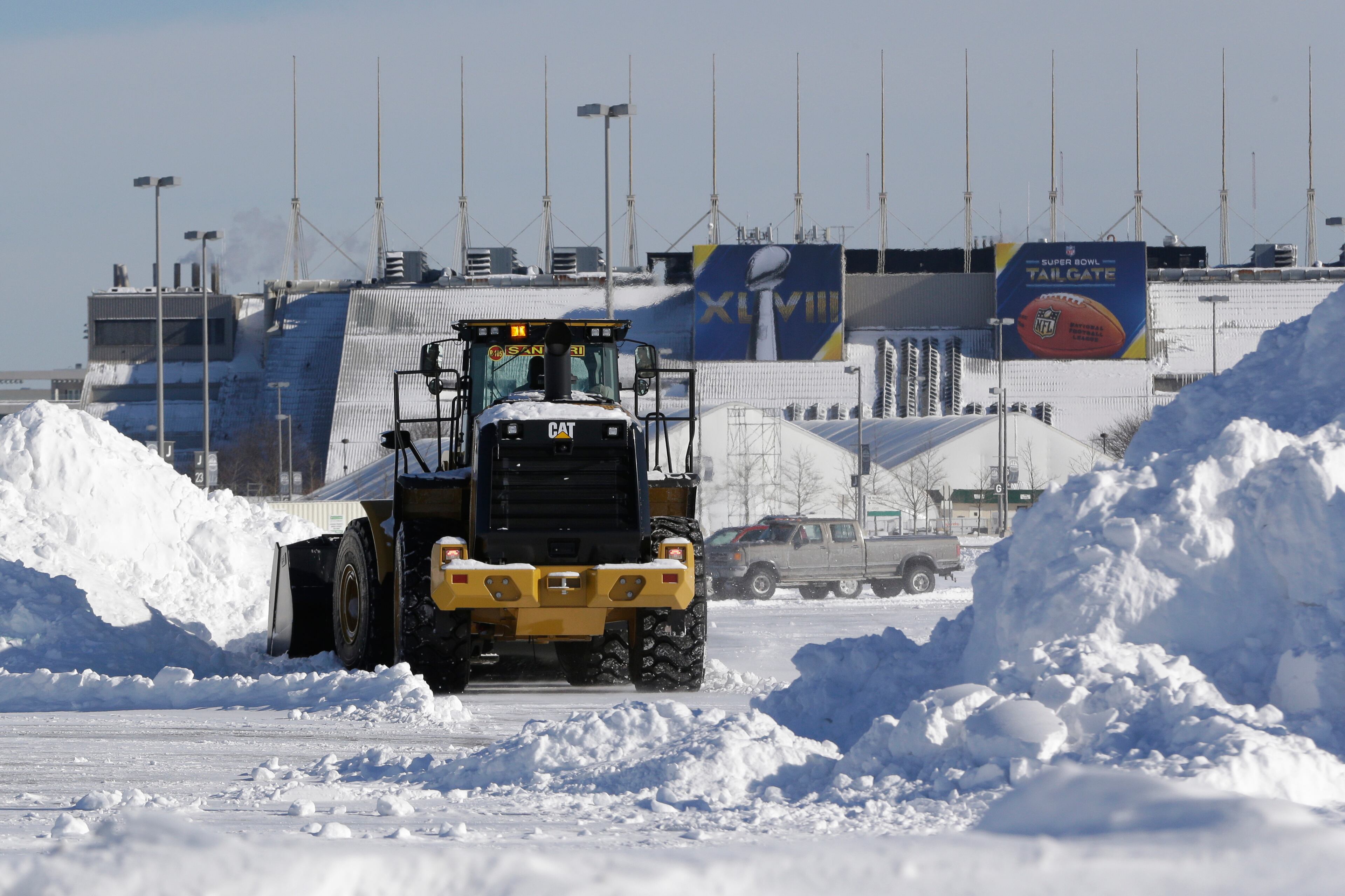 A tractor plows snow off the parking lot of MetLife Stadium as crews removed snow following a snow storm, Wednesday, Jan. 22, 2014, in East Rutherford, N.J. Super Bowl XLVIII, which will be played between the Denver Broncos and the Seattle Seahawks on Feb. 2, will be the first NFL title game held outdoors in a city where it snows. (AP Photo/Julio Cortez)