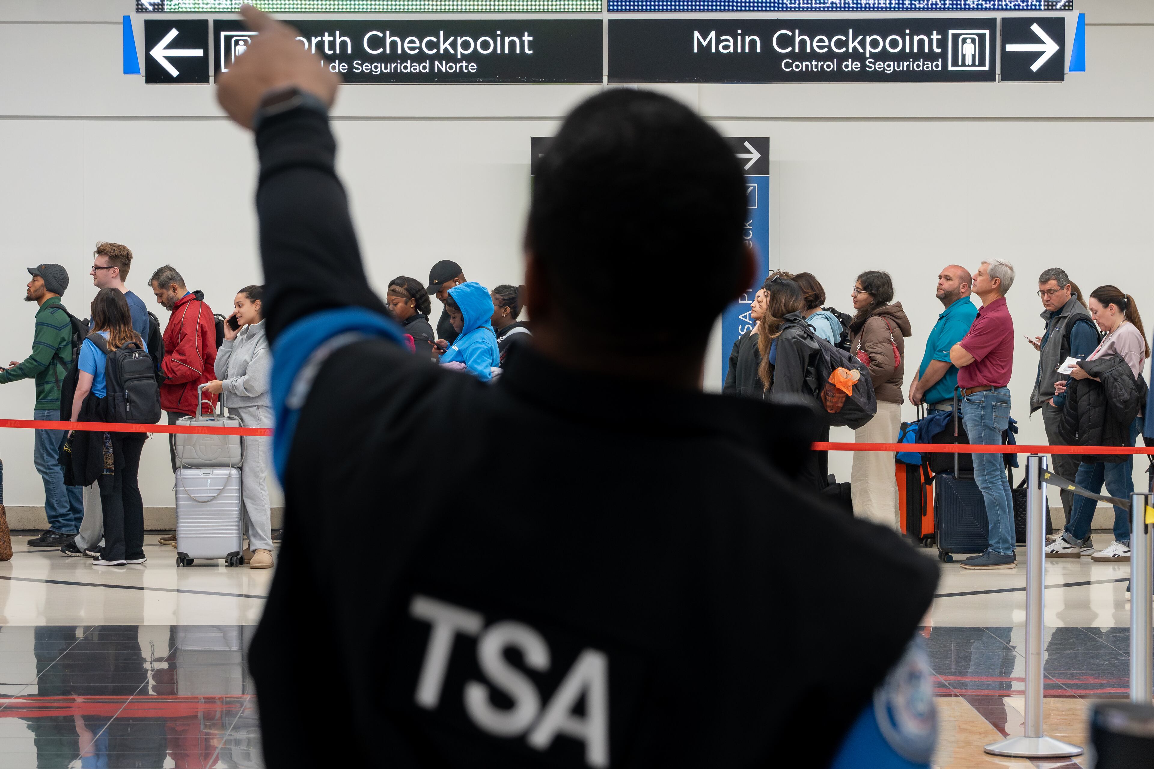 A Transportation Security Administration officer helps a traveler find the right security line at Hartsfield-Jackson Atlanta International Airport on Monday, March 9, 2026. (Ben Hendren for the AJC)
