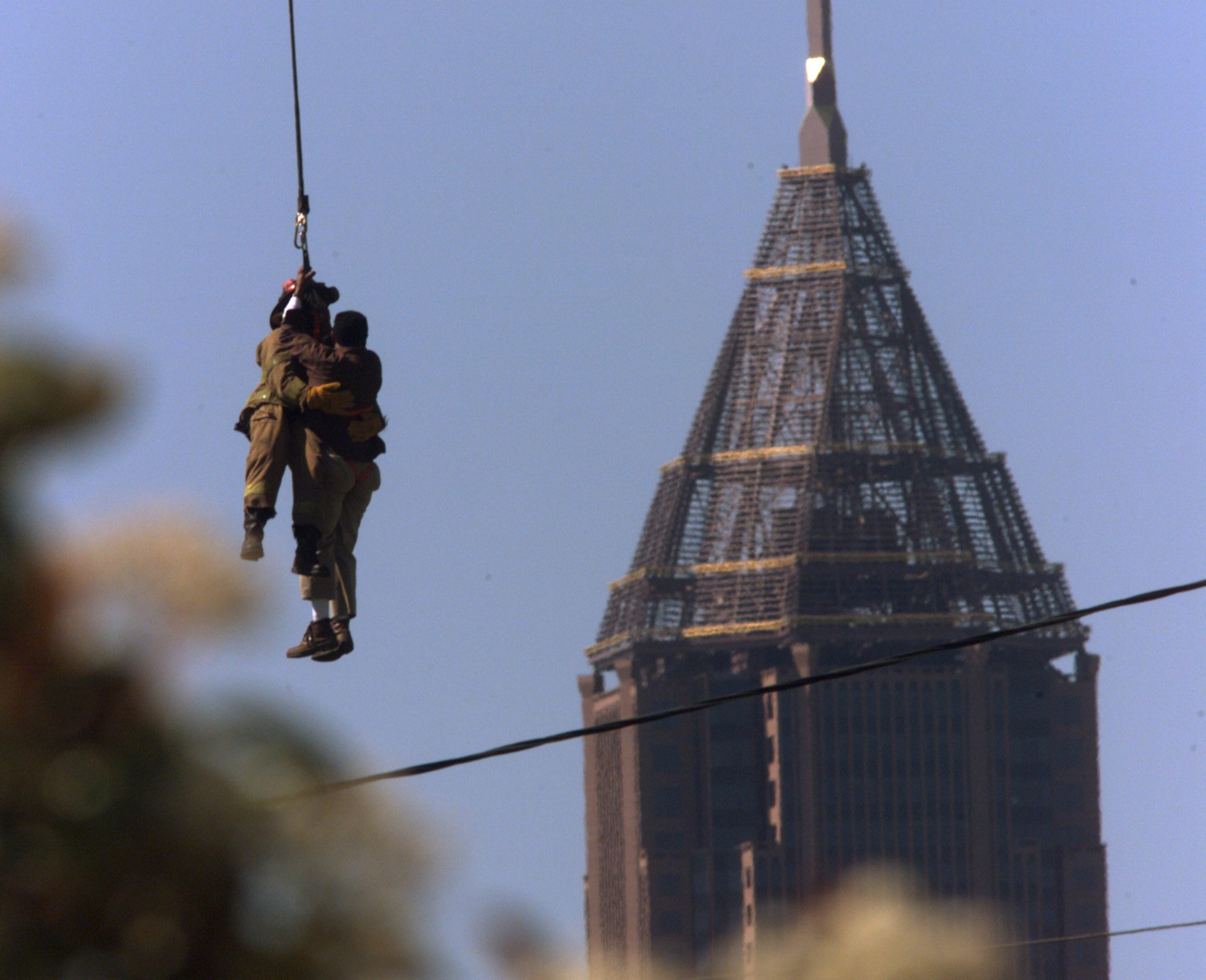 990412-04/12/99-JOHN SPINK/staff-ATLANTA/FULTON COUNTY- A 3 alarm fire at the The Fulton Cotton Mill at 170 Blvd. in Atlanta SE, Monday afternoon trapped a lone crane operator high above the inferno of flames trapping him. With fears of the crane collapsing the Atlanta fire department made a decision for a lone firefighter, Matt Mosley suspended by a helicopter to rescue the man from the tail end of the crane. Flying from an adjacent grassy area north of Oakland Cemetary, the crane operator was safely brought down to medics. Here the firefighter with operator in tow takes off.