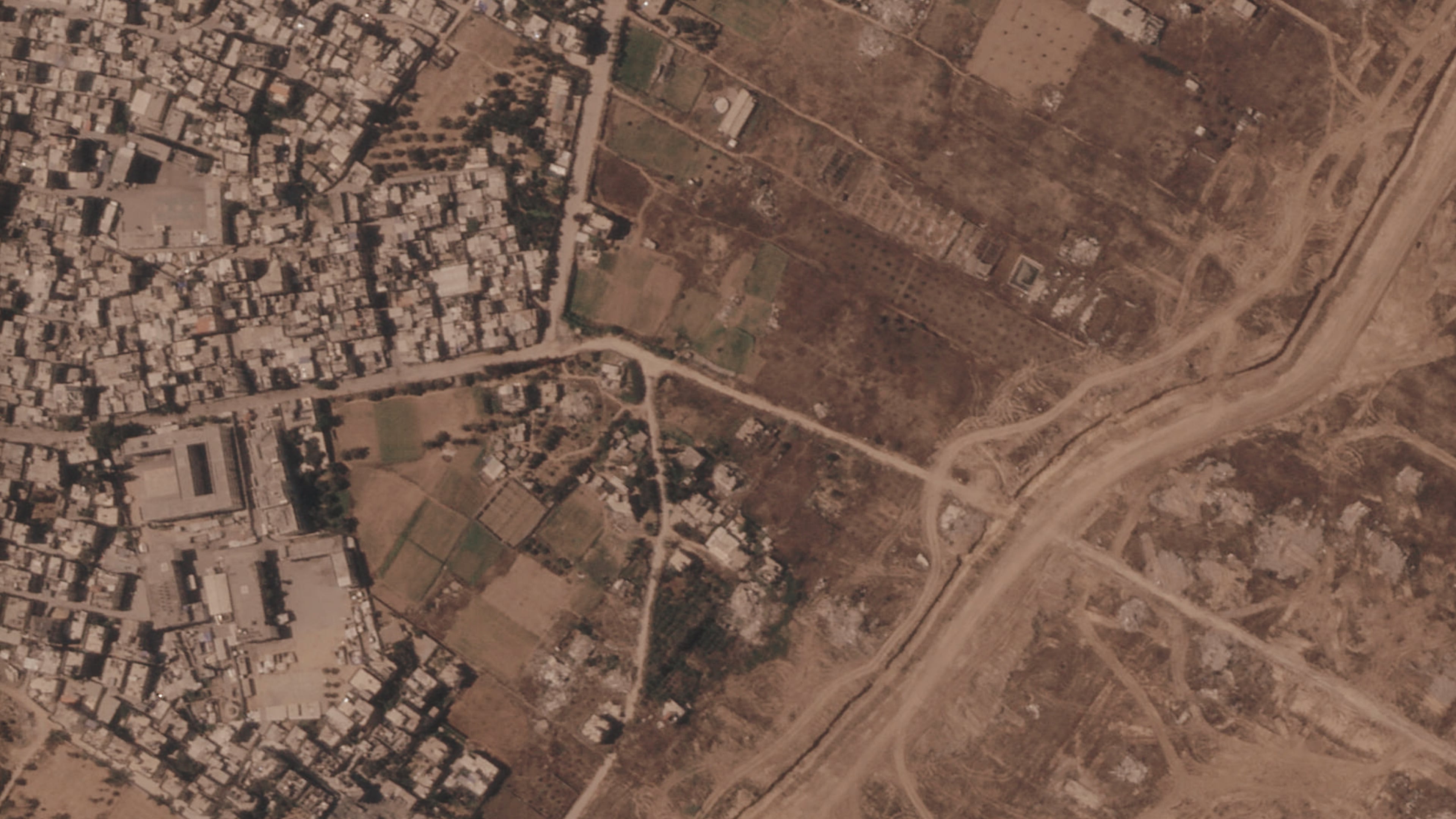 This satellite image from Planet Labs PBC shows a section of an earthen barrier being built by the Israeli military, right side of image moving top to bottom, in the central Gaza Strip, July 1, 2026. At left is the Maghazi refugee camp, and on the other side are homes demolished by the military. (Planet Labs PBC via AP)