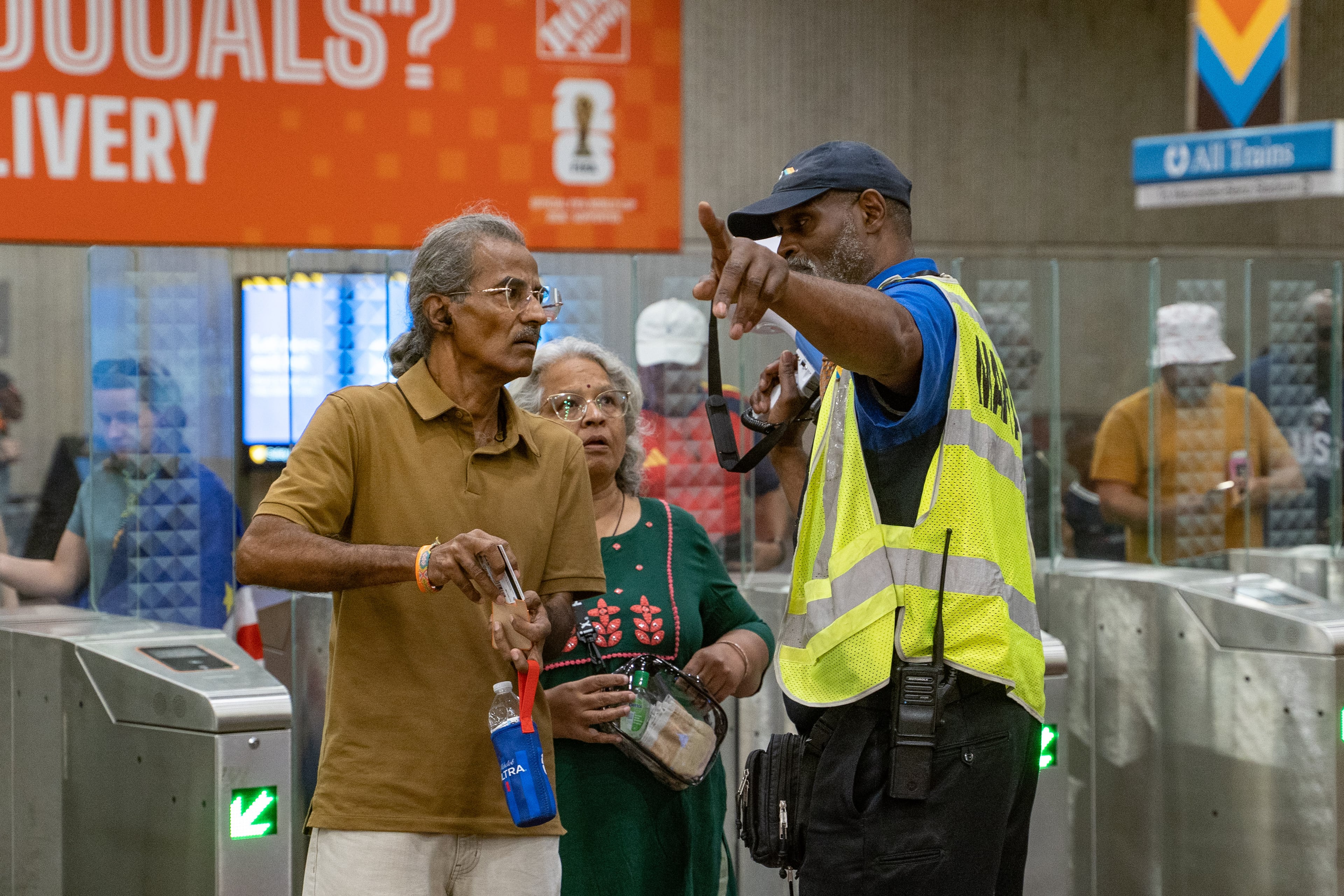 A MARTA Ambassador helps a man and woman Inside the SEC District MARTA station as fans attend the first FIFA match held in Atlanta on Monday, June 15, 2026. (Ben Hendren for the AJC)