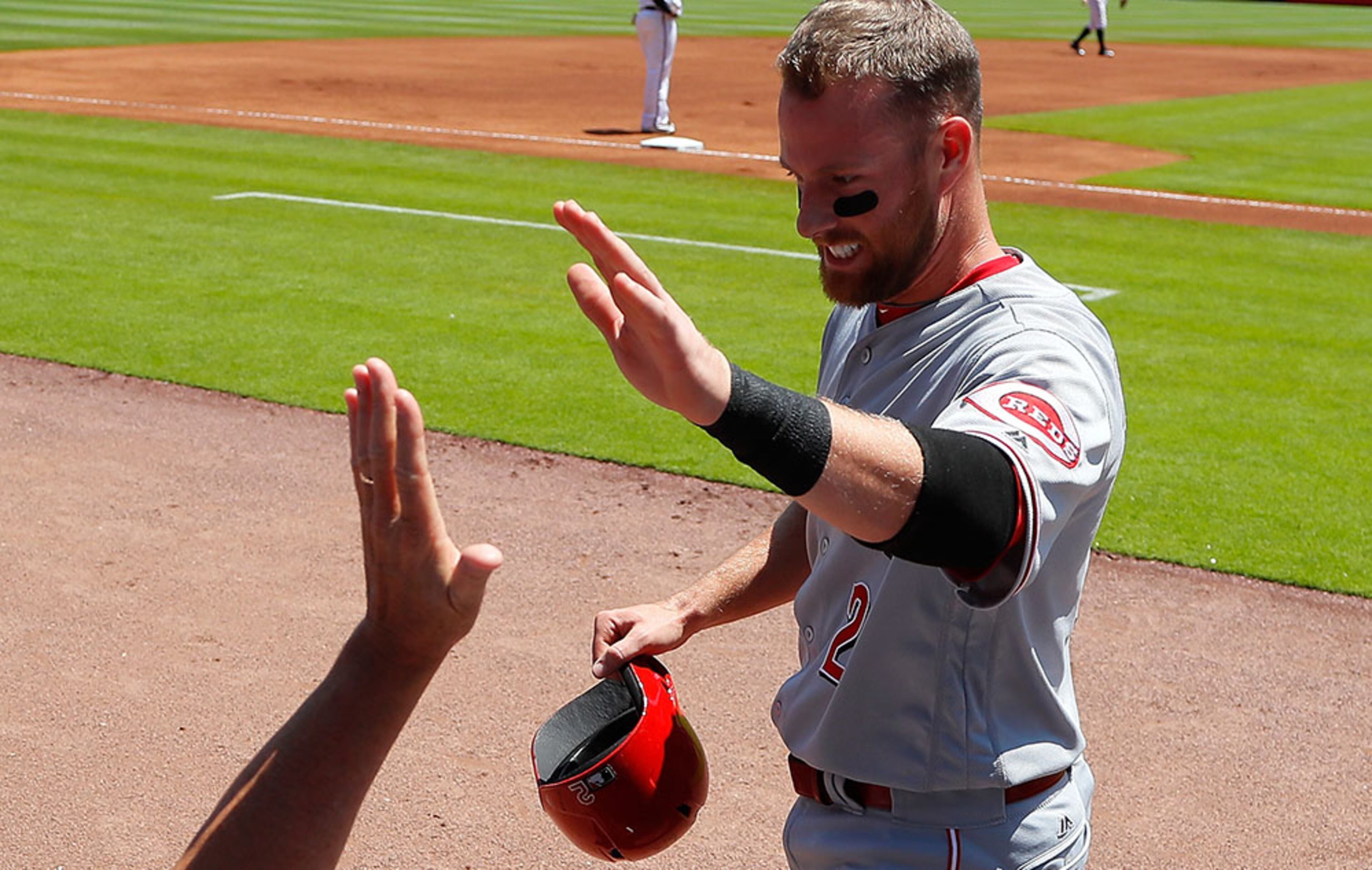 Zack Cozart, of the Cincinnati Reds, is congratulated by teammates in the dugout after scoring on a single hit by Brandon Phillips in the first inning against the Braves June 16, 2016, at Turner Field in Atlanta.