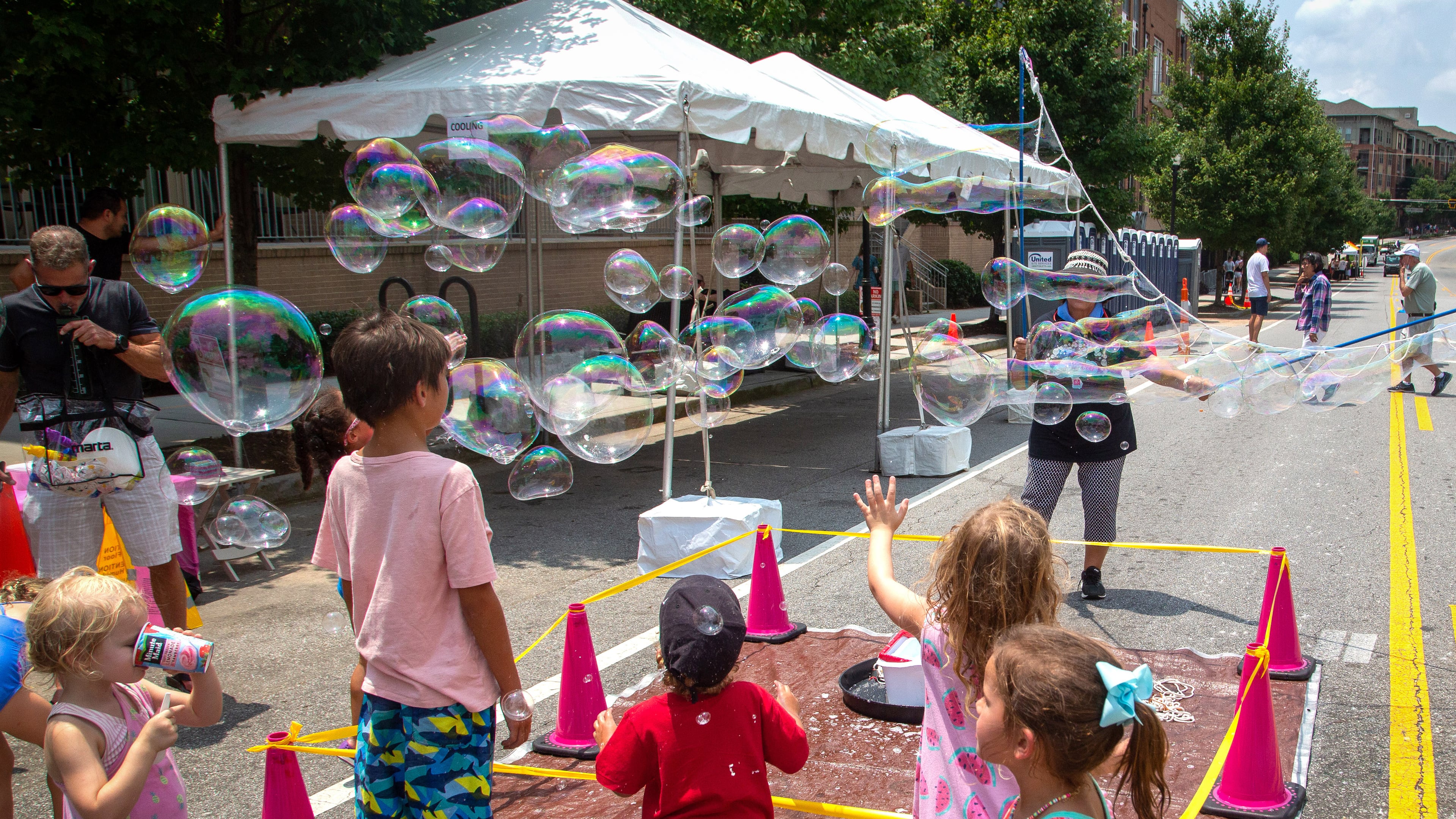 Kids pop large bubbles created by Deborah Mosher during the Brookhaven Cherry Blossom Festival Saturday, July 31, 2021. STEVE SCHAEFER FOR THE ATLANTA JOURNAL-CONSTITUTION