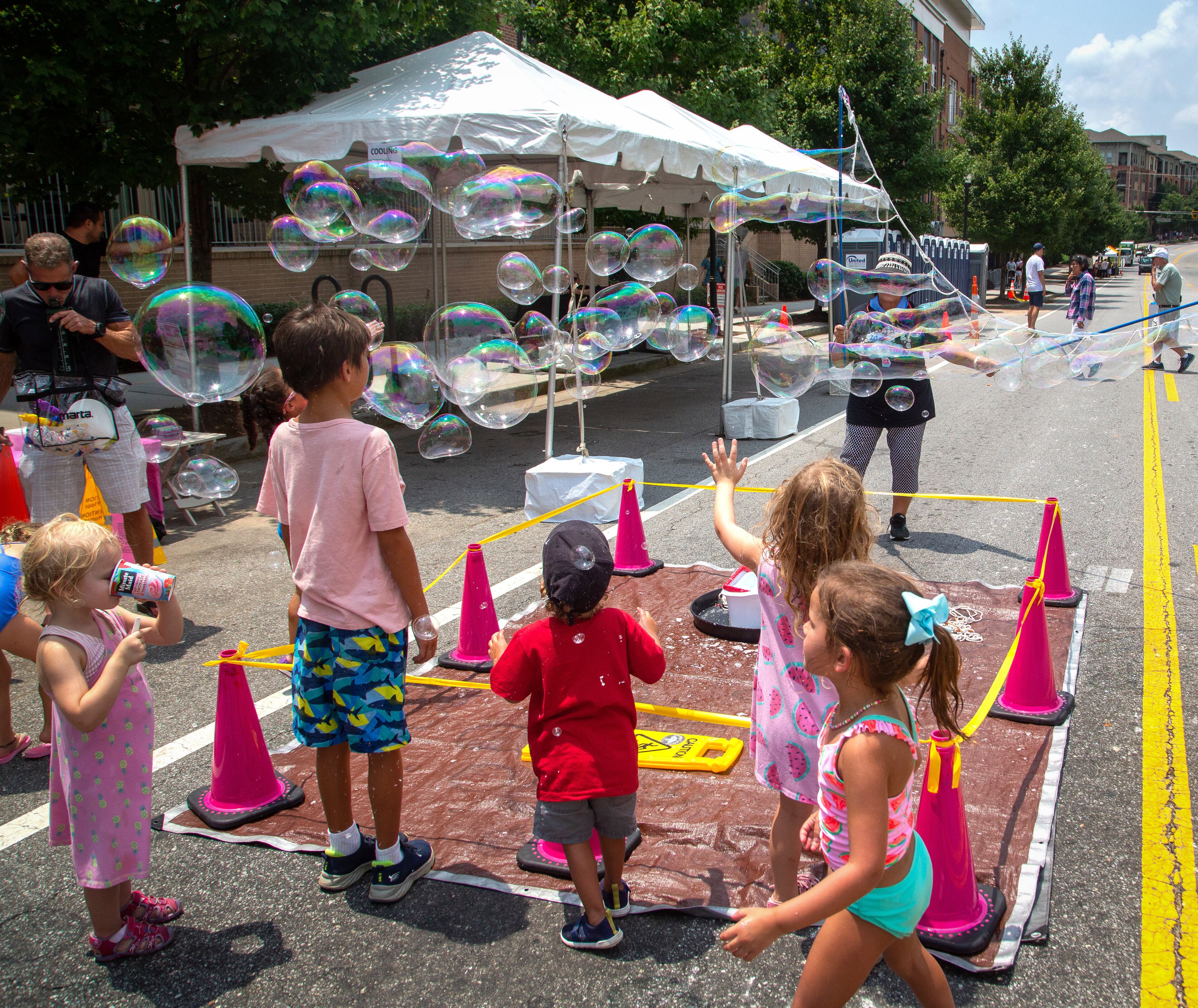 Kids pop large bubbles created by Deborah Mosher during the Brookhaven Cherry Blossom Festival on Saturday, July 31, 2021. STEVE SCHAEFER FOR THE ATLANTA JOURNAL-CONSTITUTION