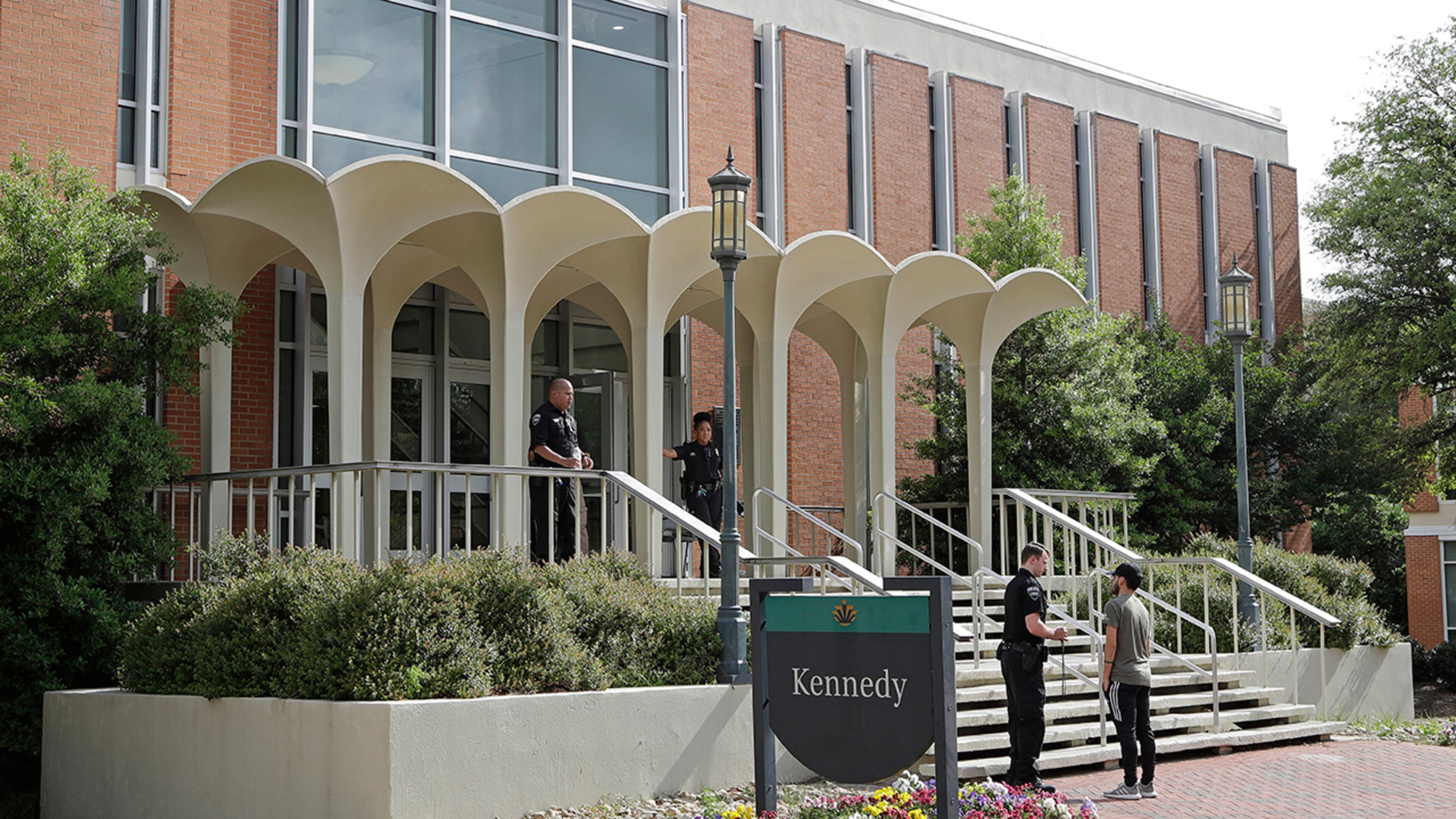 Campus police talk to a student, Wednesday, May 1, 2019, outside the building where two people were killed the day before at the University of North Carolina-Charlotte in Charlotte, N.C. (AP Photo/Chuck Burton)