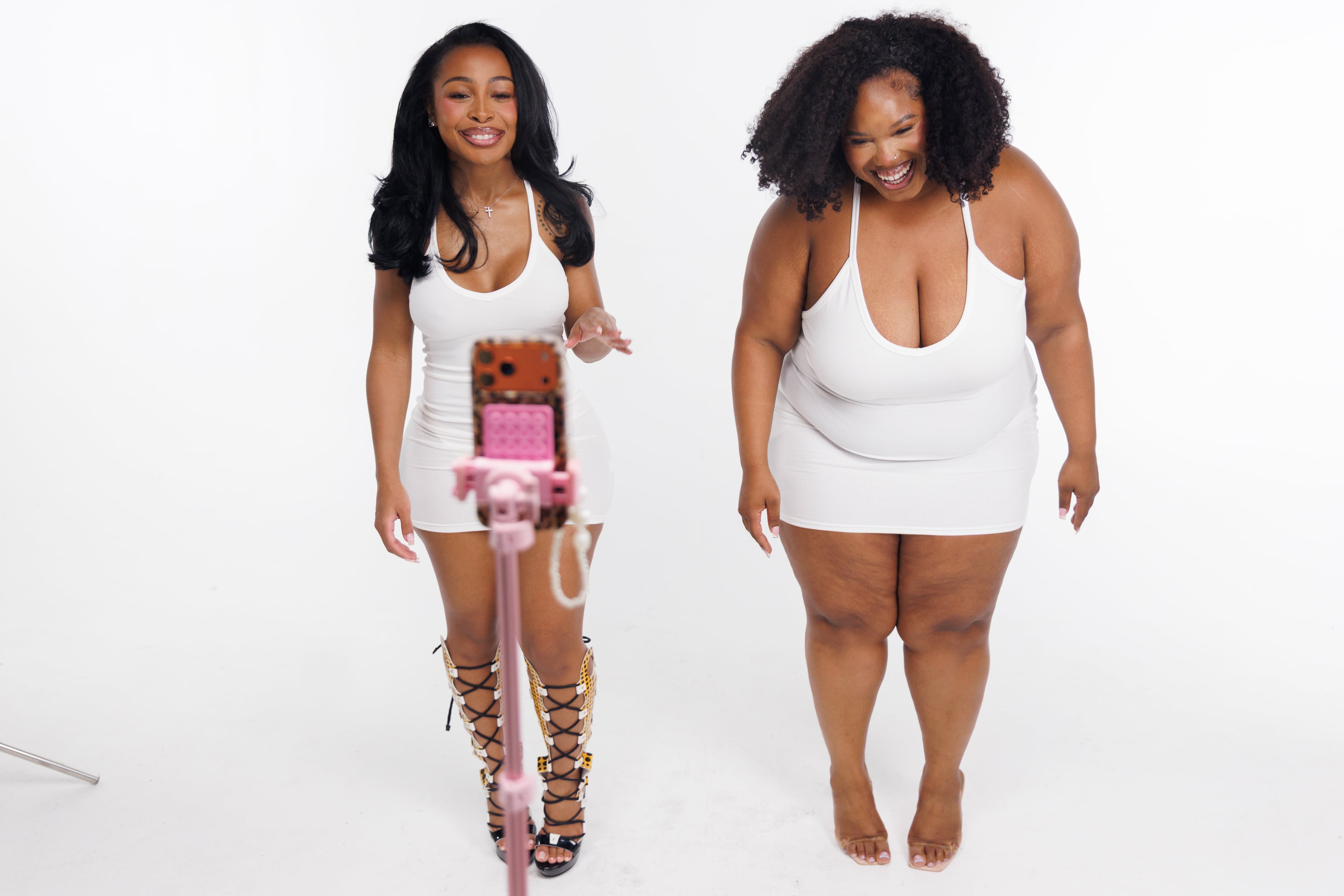 Entrepreneur and influencer Jayda Cheaves, left, and model Omeshia Ferguson, right, make a TikTok in the middle of a photo shoot for the new Waydamin clothing line, Friday, May 29, 2026 in Atlanta. Cheaves has 4.7 million TikTok followers. (Estela Muñoz/AJC)
