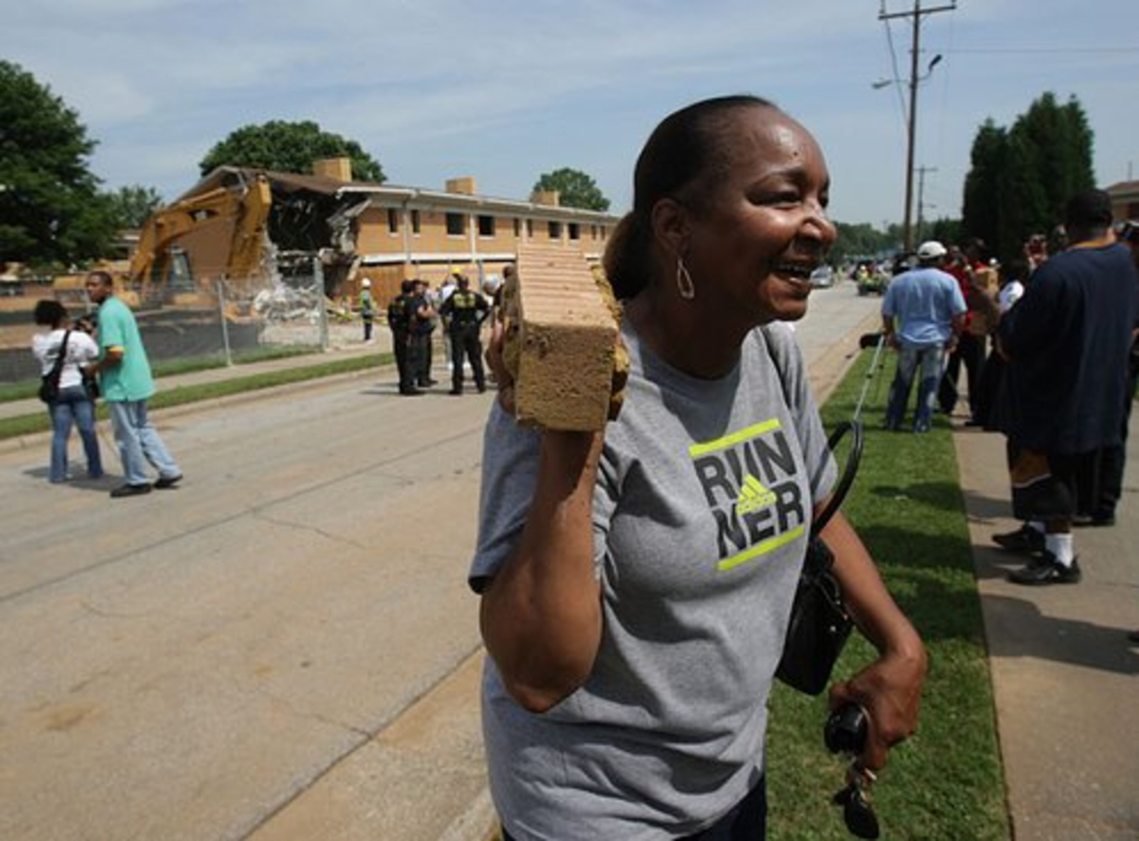 Glenda McKennie, a former librarian at Bowen Homes, carries a brick from the demolition.