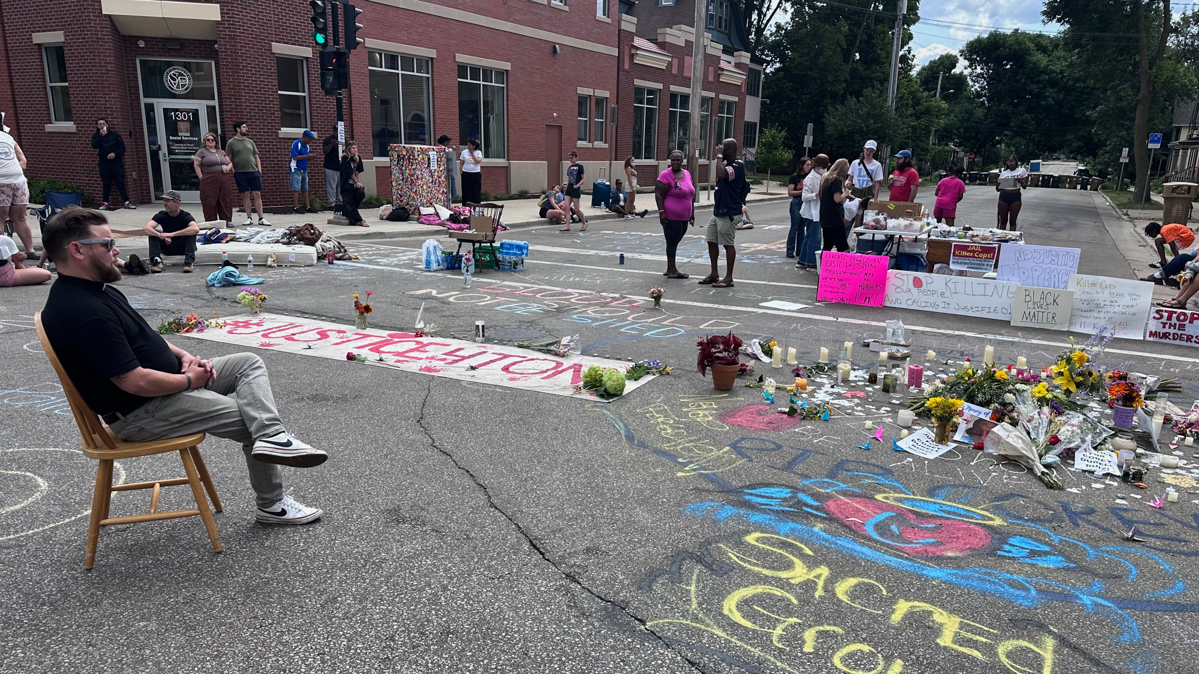 Mourners gather around a memorial at the site where a man was shot and killed on Wednesday by Madison police, Thursday, July 23, 2026, in Madison, Wis. (AP Photo/Scott Bauer)