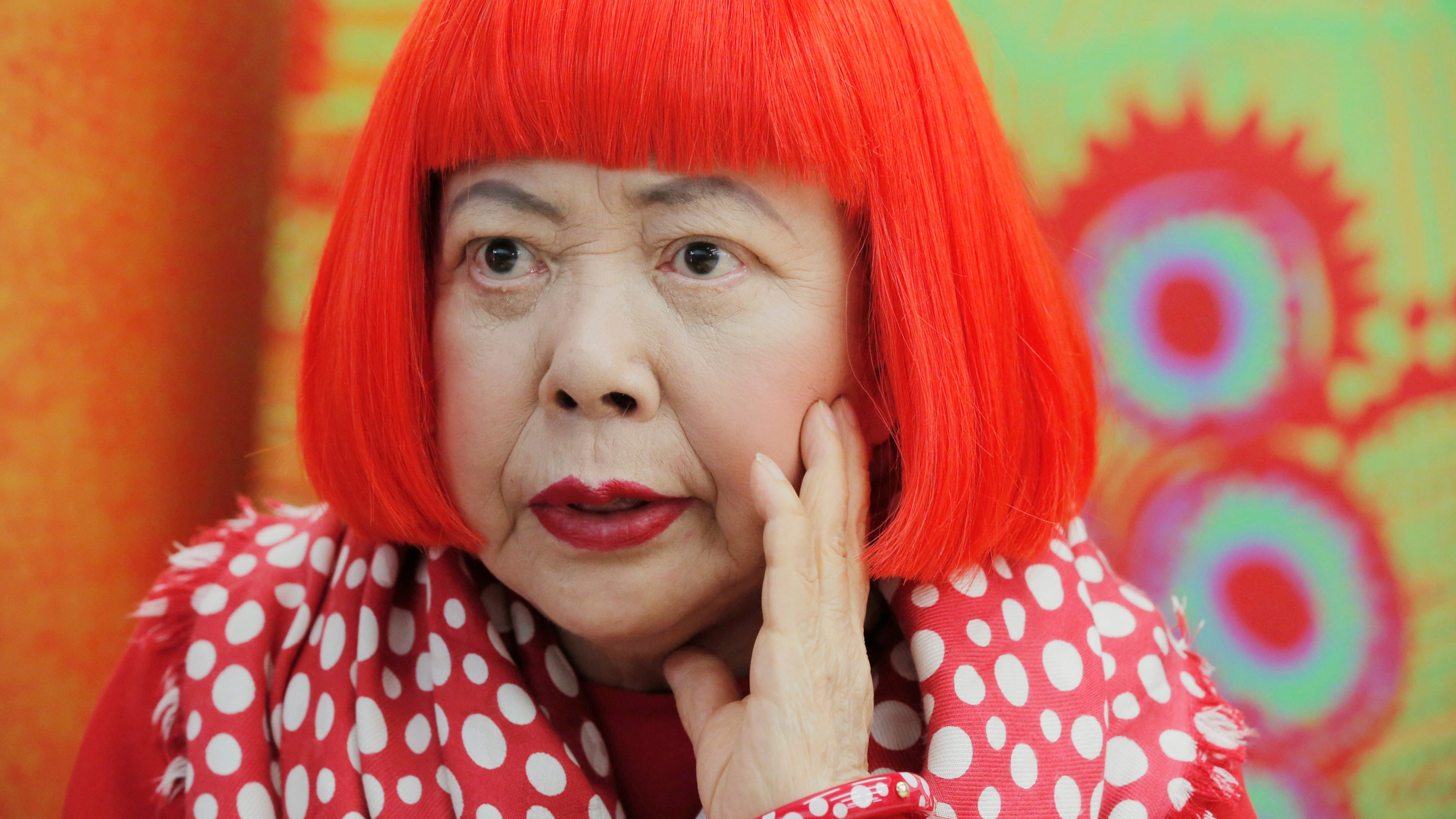 FILE - Japanese avant-garde artist Yayoi Kusama, wearing a bright red wig and a Louis Vuitton polka dot scarf, speaks during an interview at her studio in Tokyo, on Aug. 1, 2012. (AP Photo/Itsuo Inouye, File)