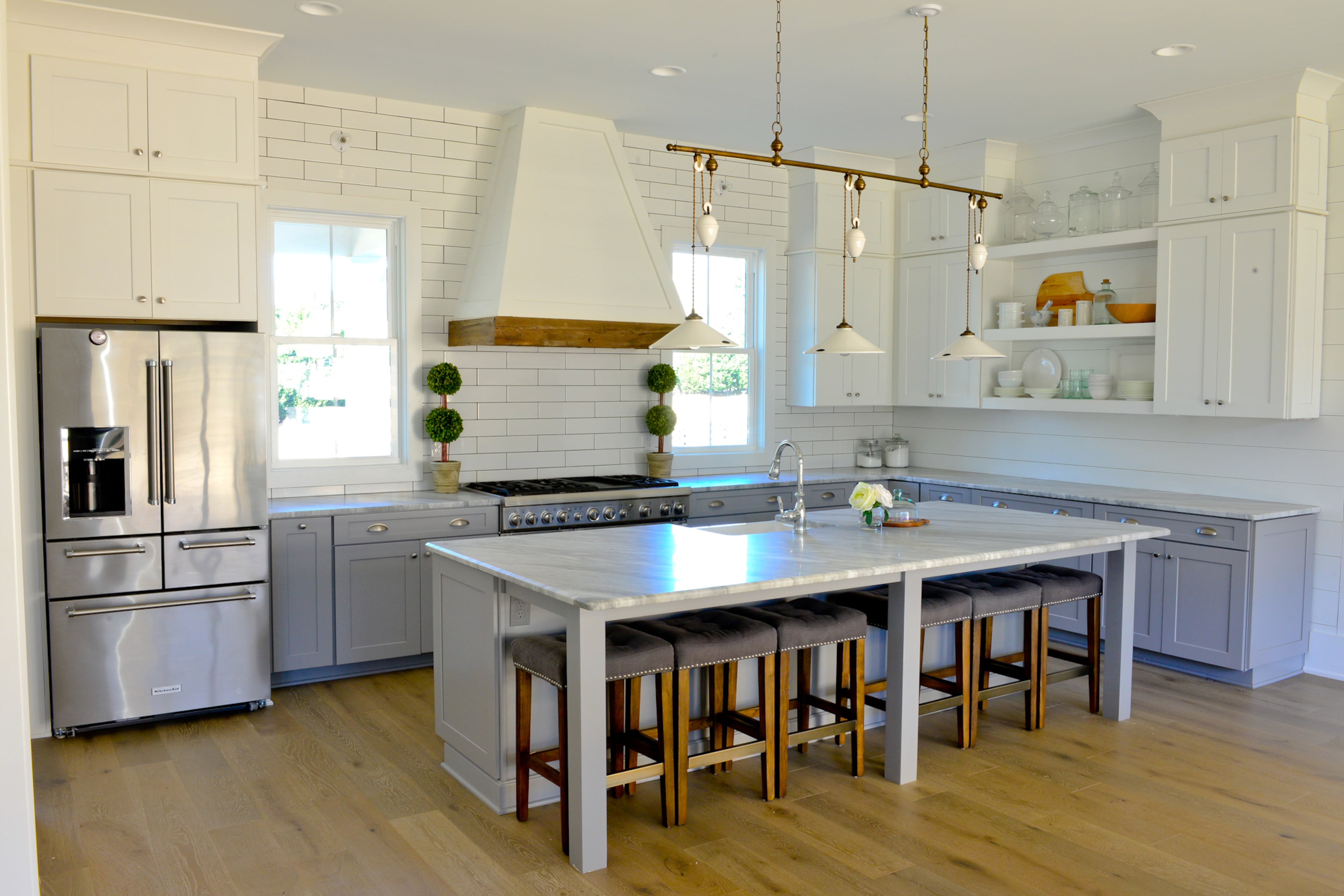 Carrera marble counters, Kingston oak 7-inch engineered wood flooring from Shaw and Timberlake shaker cabinets are the foundation for this open modern farmhouse kitchen in Milton. Tucked under the expansive island are kitchen stools from Four Hands.