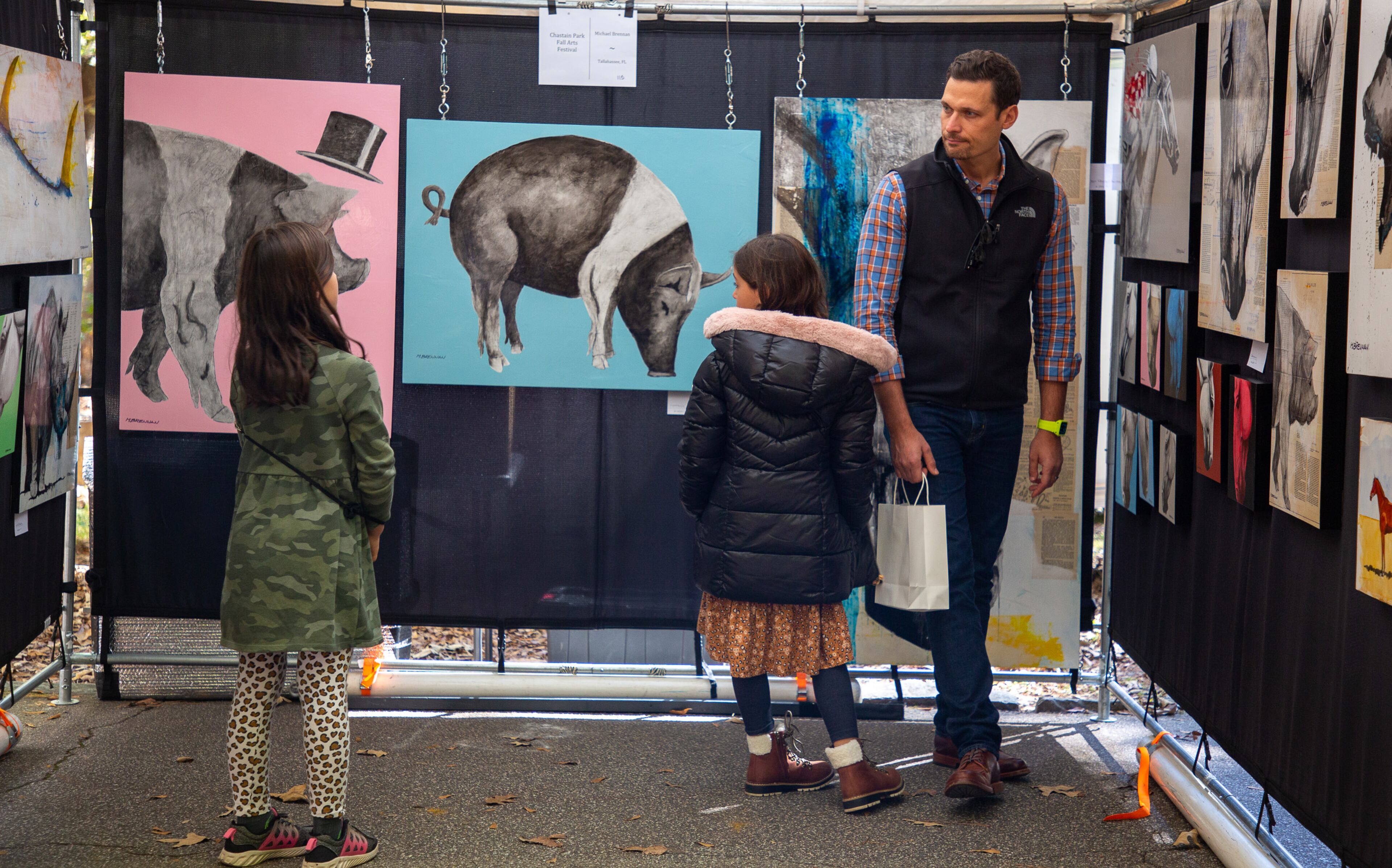 People look over the paintings of Michael Brennan during the Chastain Park Fall Arts Festival Sunday, November 7, 2021. STEVE SCHAEFER FOR THE ATLANTA JOURNAL-CONSTITUTION