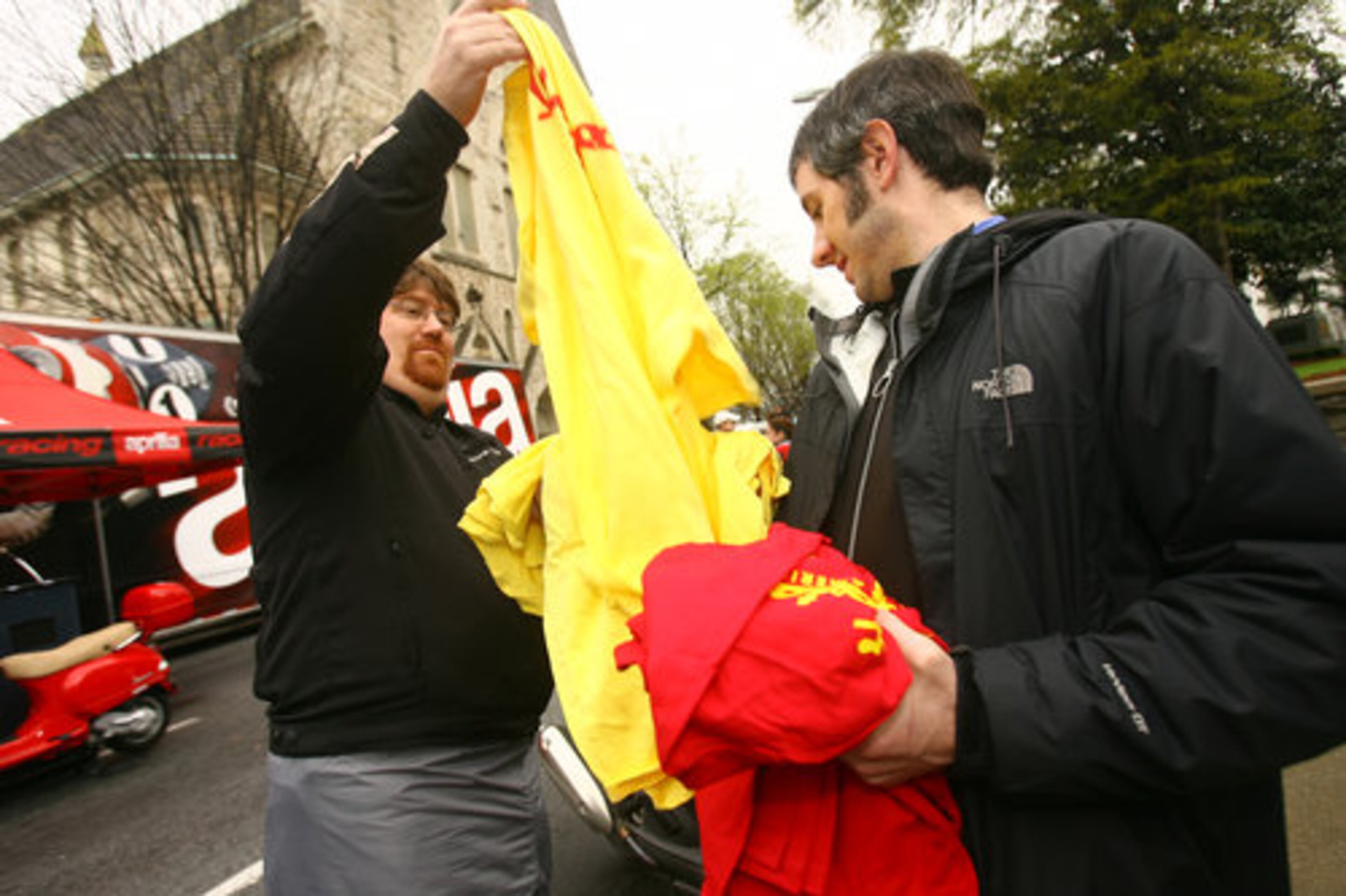 Mike Bautsch (left) of Marietta takes a free t-shirt from Ted Daugherty (right) of Decatur, who works for the Scooter Superstore.