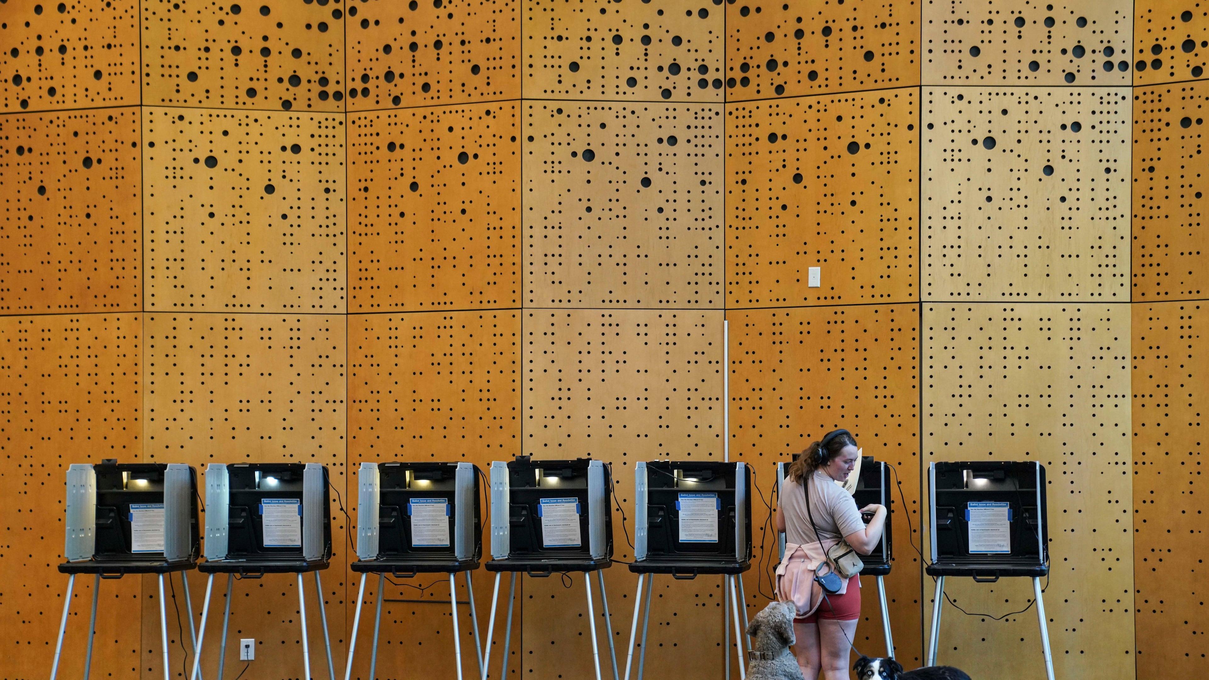 Danielle Grisolano brings her dogs Lincoln and Pepper with her to vote in the Democratic primaries at Denver Public Library, Tuesday, June 30, 2026, in Denver. (AP Photo/Rebecca Slezak)