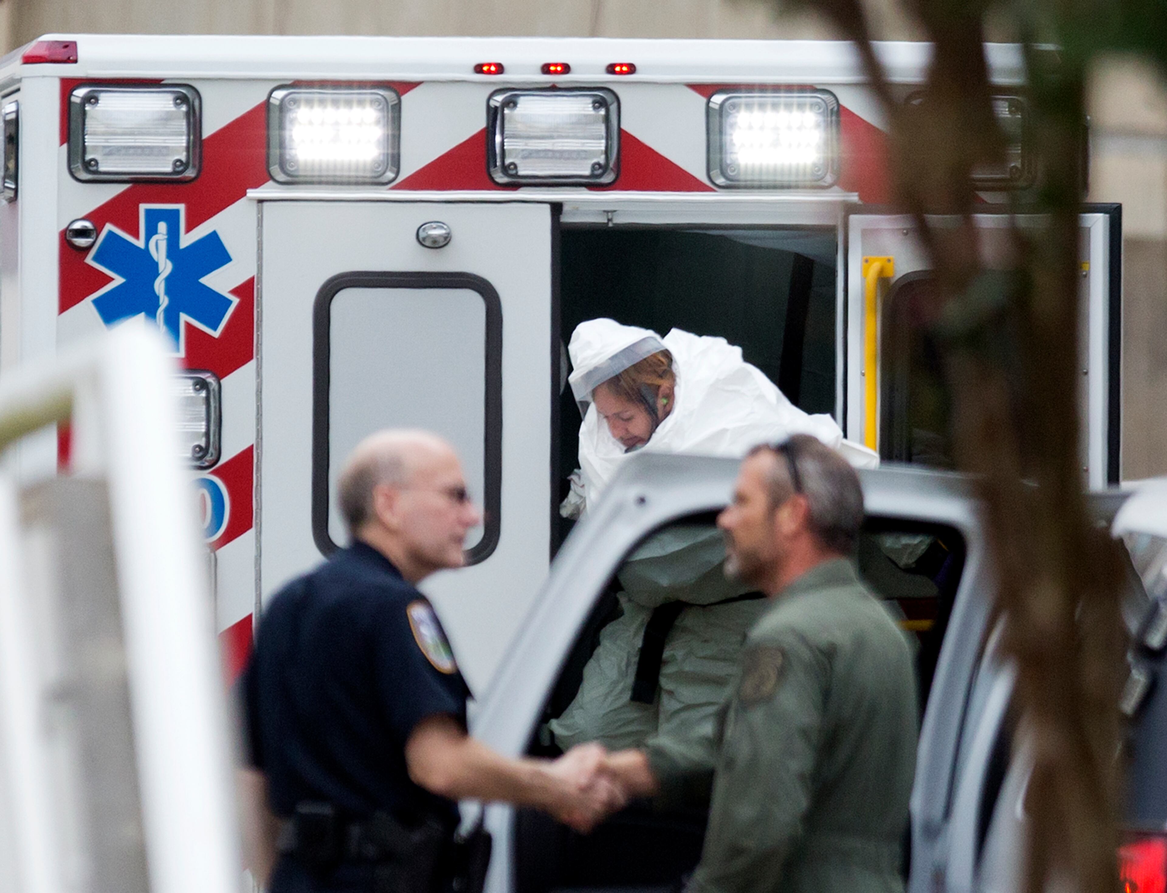 A person wearing a haz-mat suit steps out of an ambulance as an ebola patient arrives for treatment, Tuesday, Sept. 9, 2014, in Atlanta. The fourth American aid worker sickened with the Ebola virus arrived Tuesday morning for treatment at Emory University Hospital, where two others have been successfully treated. (AP Photo/David Goldman)