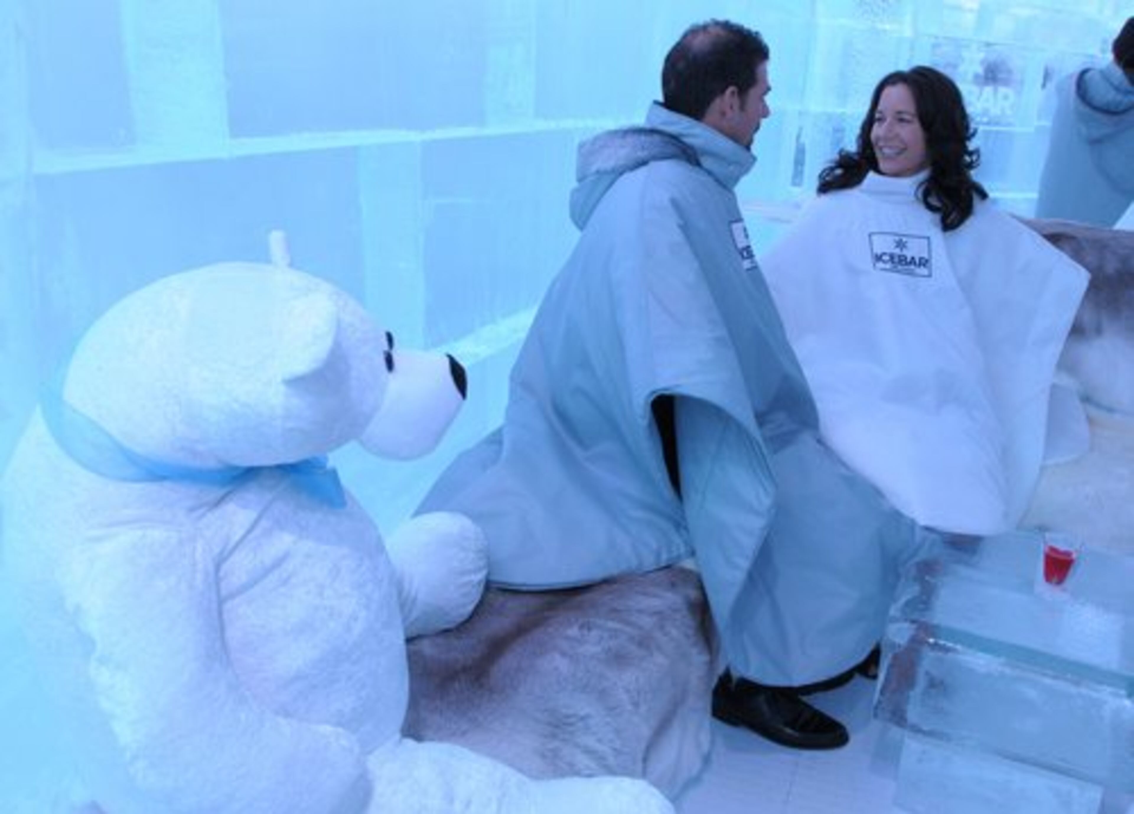 Paul and Victoria Goddard chat while sitting on fur-lined ice furniture inside ICEBAR Orlando. One guest remarks, "It's great that Orlando now has a winter."
