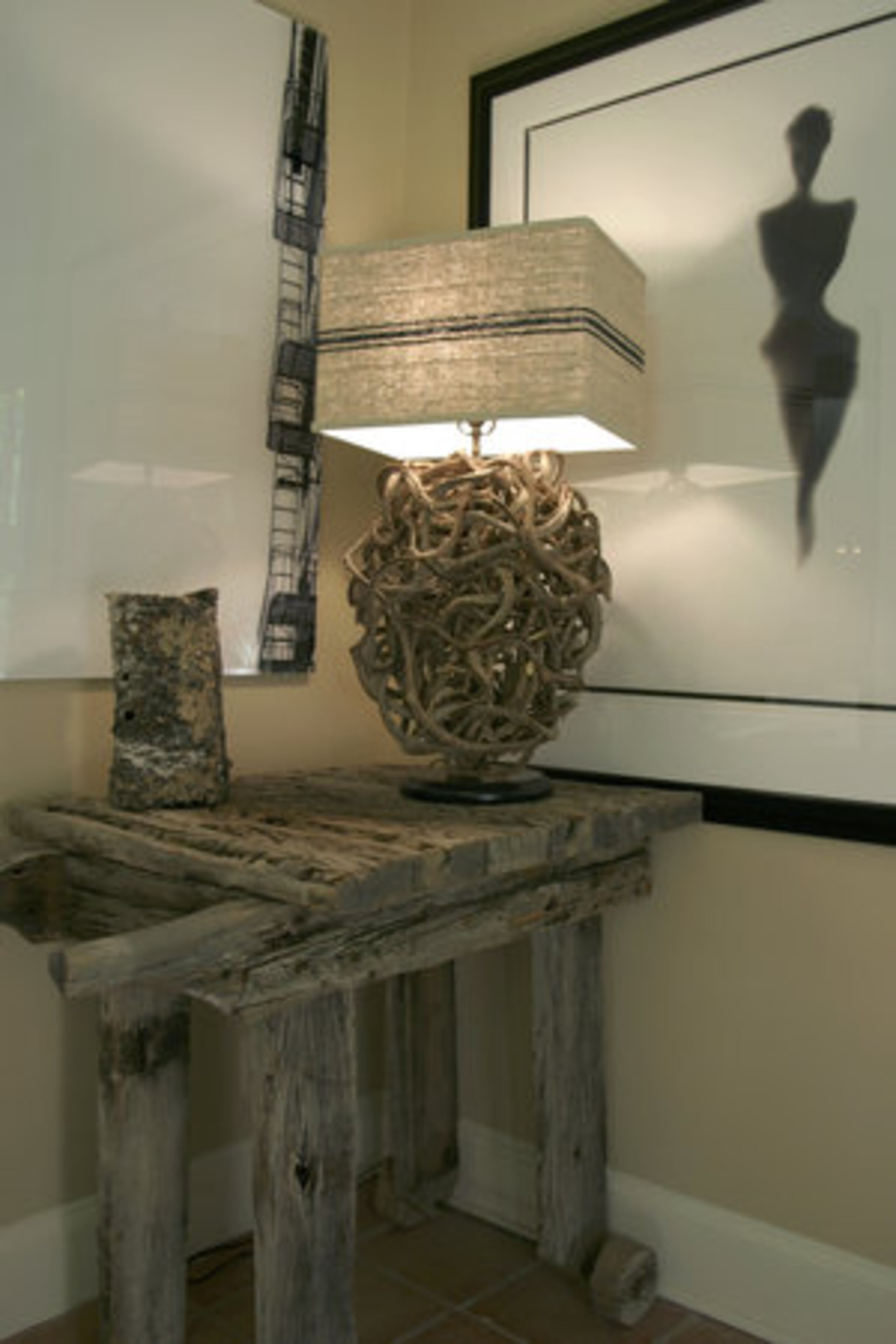 This table with a natural weathered patina was found at a garage sale and was destined for the porch, but Mary appointed it to a corner in the office. It's flanked by "Fire Escape" (left) by Jeff Jones, and a silhouette by Rob Brinson. The lamp is made from a vine found in Vietnam - while the vine is green it is sculpted. "I take the sculpted pieces and design the lamp with a shade I design with vintage linen," explains Mary. "You'll see this same sculpted lamp at the new St. Regis Hotel."