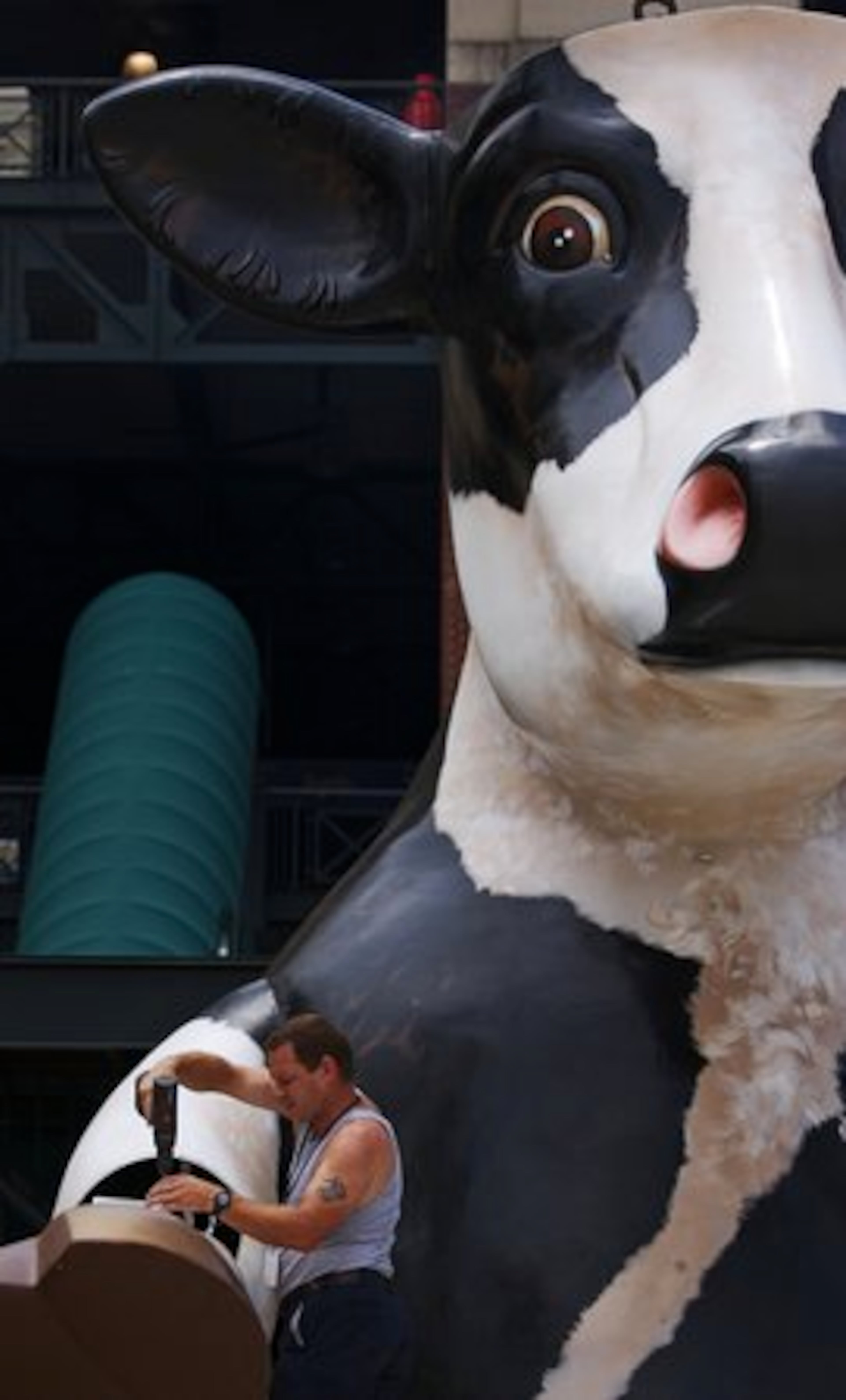 Brett Boudreaux of Kern Studios works on Chick-fil-A's tomahawk chopping cow before it's hoisted above Turner Field.
