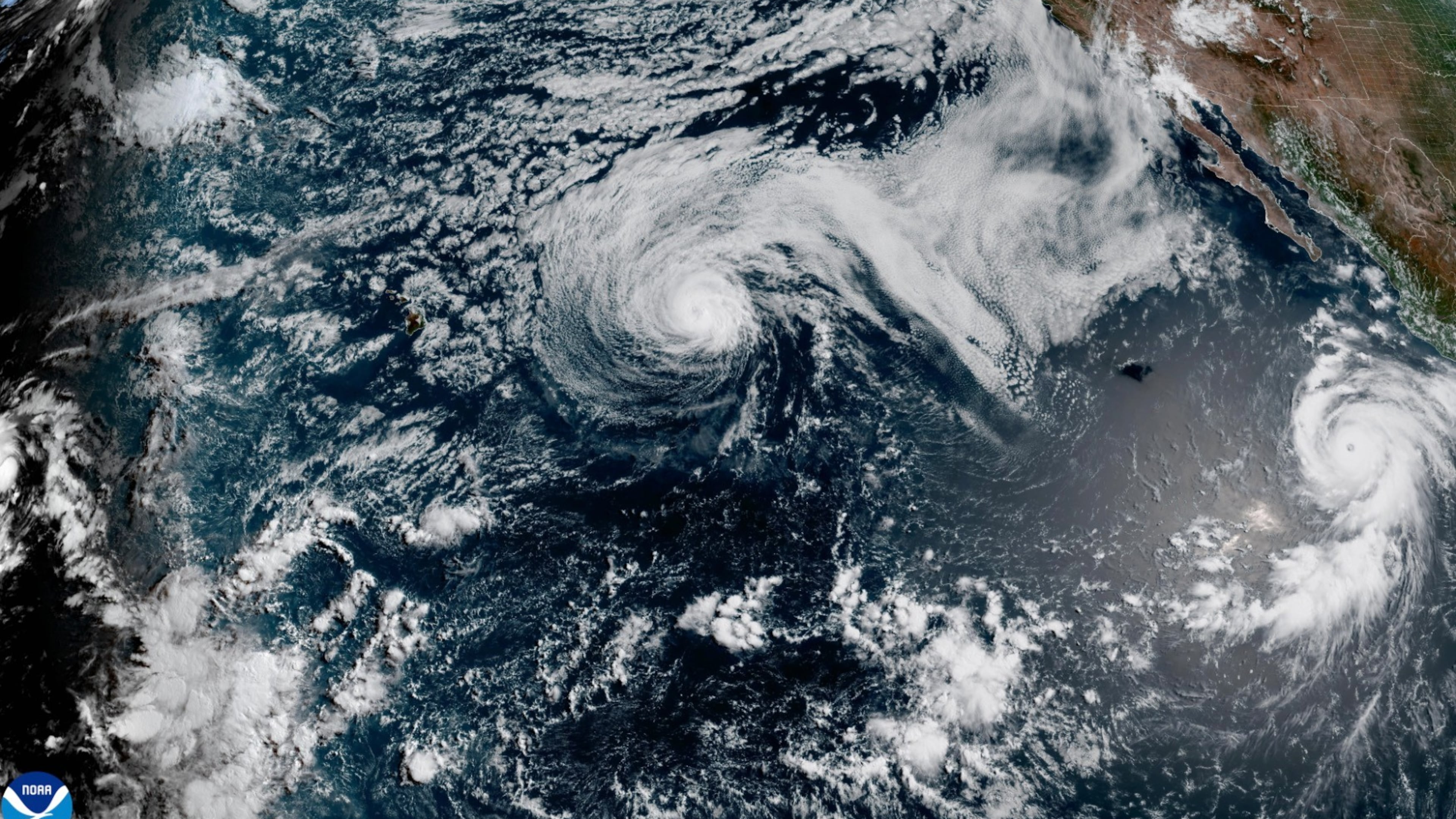 This satellite image released by NOAA shows Hurricane Fausto, center, and Hurricane Genevieve off the southwest coast of Mexico, right, over the Pacific Ocean, Sunday, July 26, 2026. (NOAA via AP)