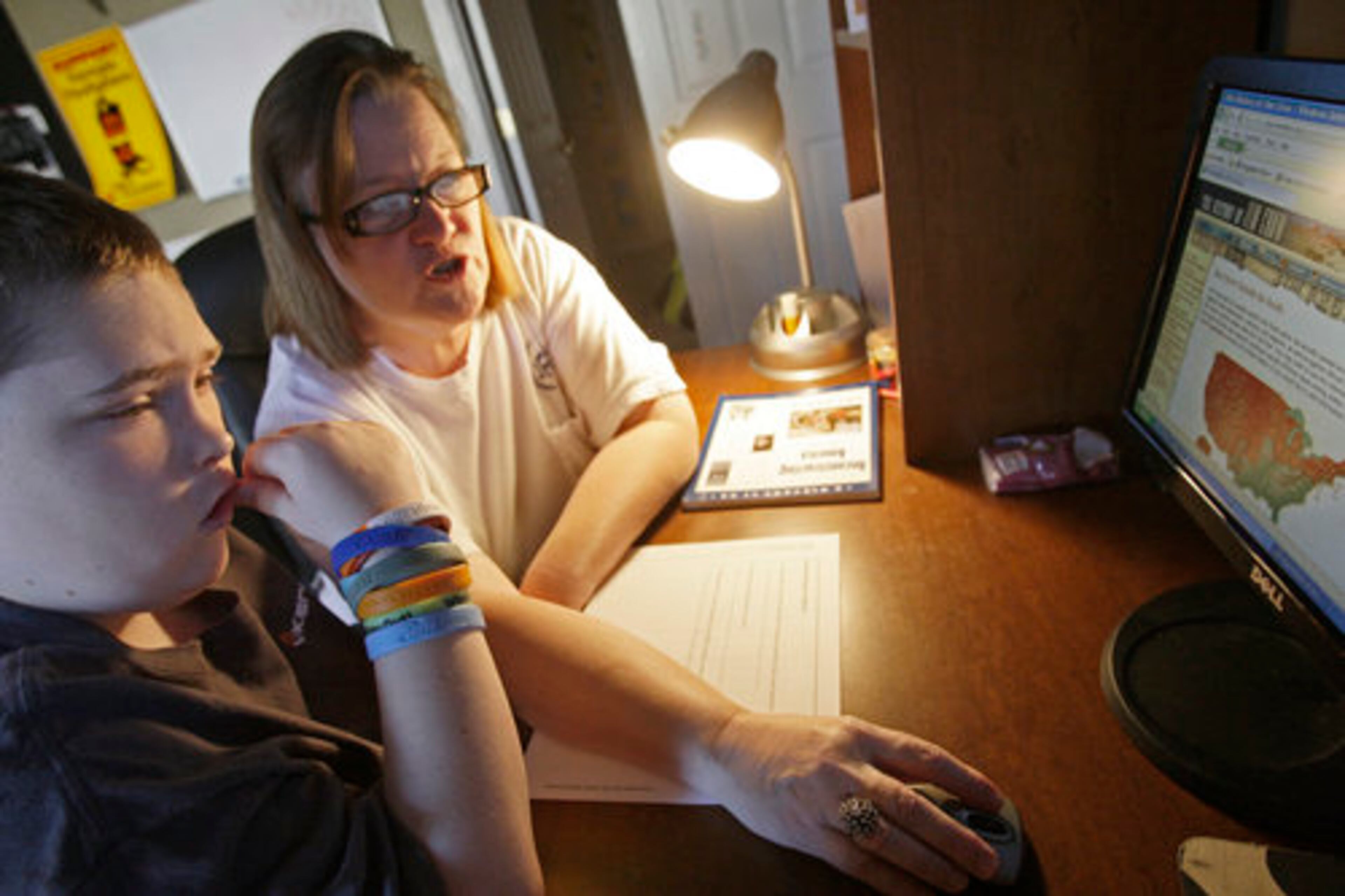 Donna Sellers works with her son, John, on his social studies lesson in Georgia Virtual Academy. Students take lessons online and use the chat function to interact with their teacher.