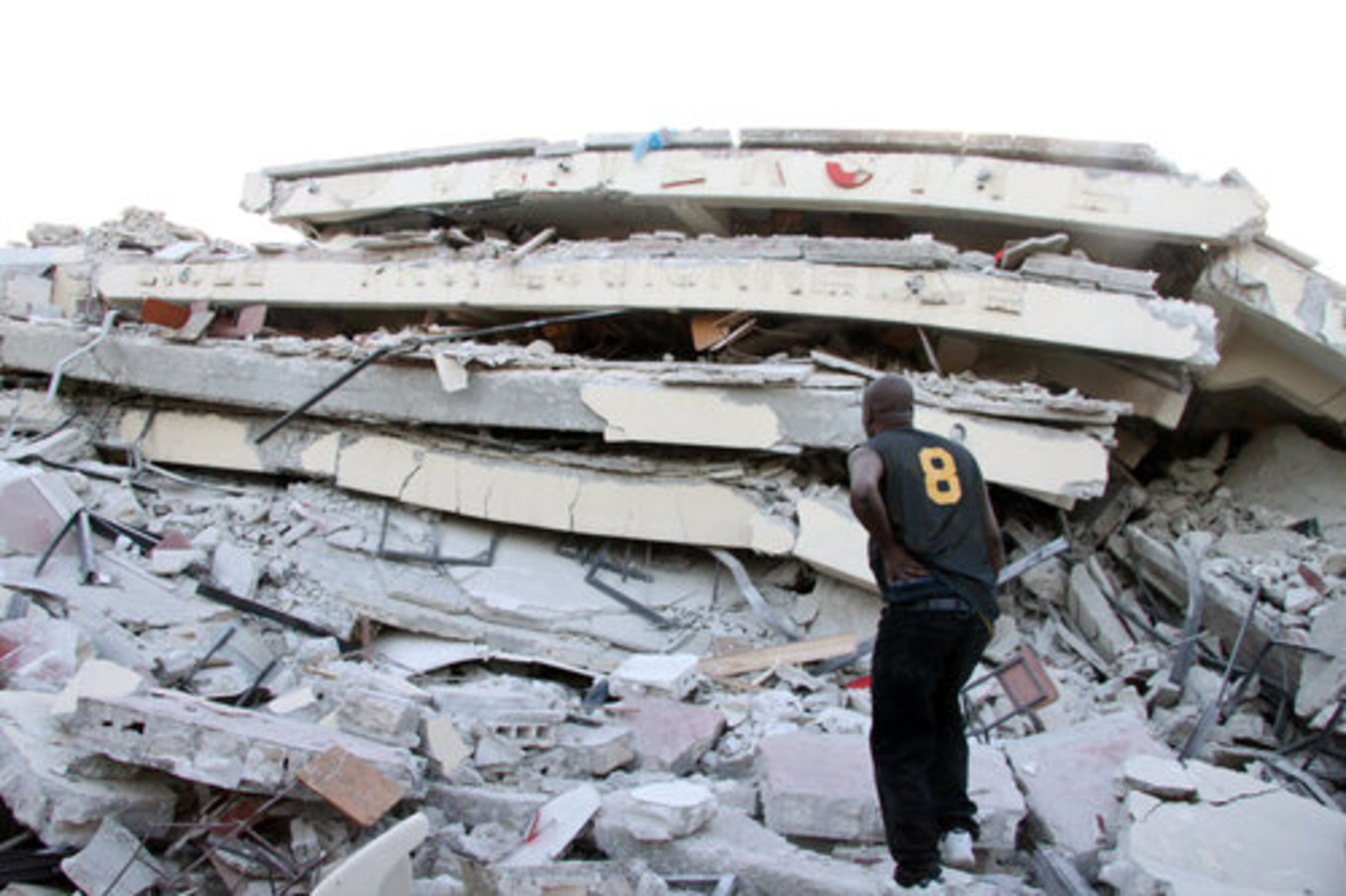 A man looks at the wreckage of a collapsed building in Port-au-Prince, Haiti, on Wednesday, Jan. 13, 2010. Huge swaths of Port-au-Prince lay in ruins, and thousands of people were feared dead in the rubble of government buildings, foreign aid headquarters and shantytowns that collapsed a day earlier in a powerful earthquake.