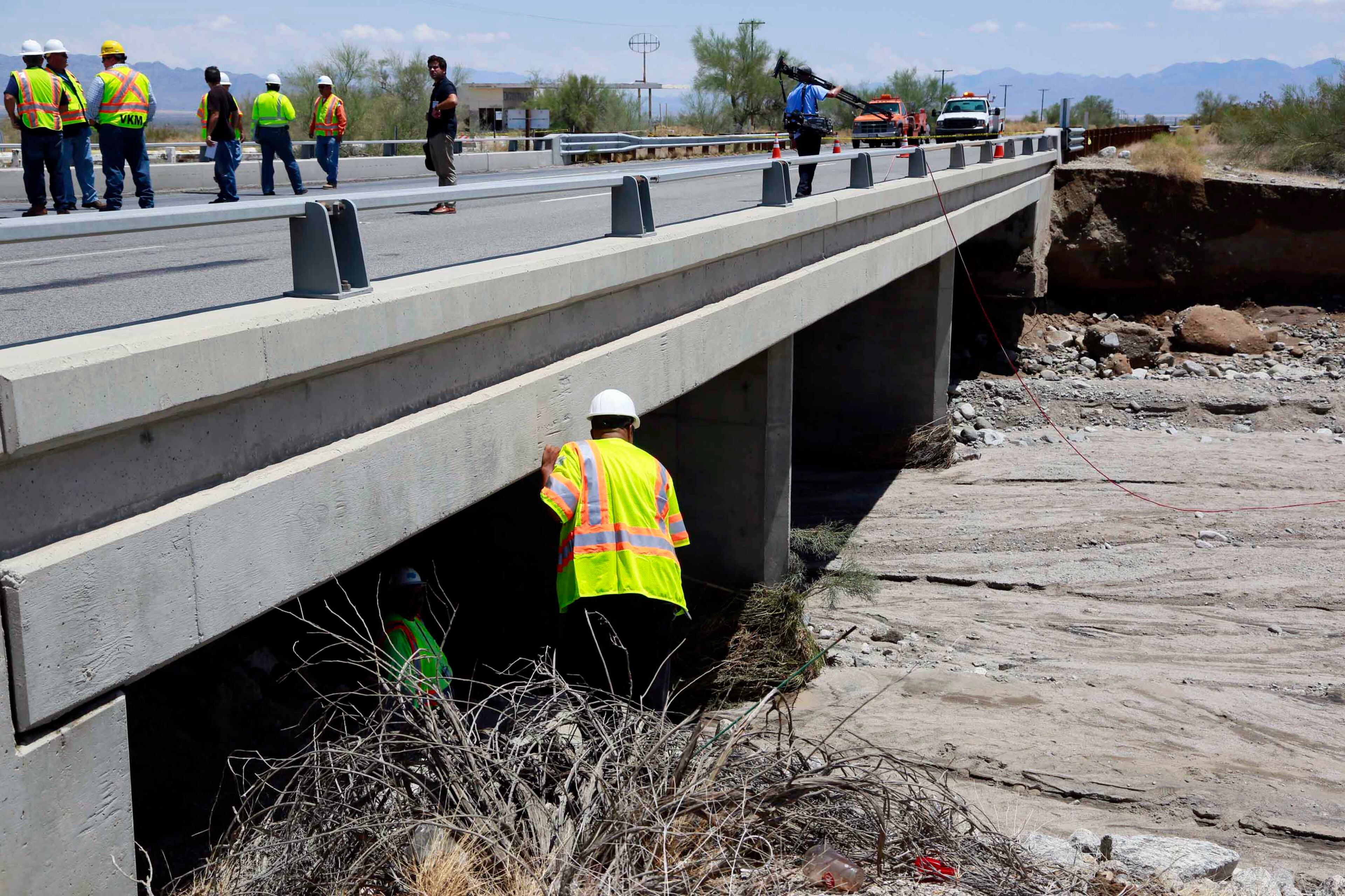 Inspectors for the California Department of Transportation inspect a west bound bridge for damage next to the bridge that was washed out along Interstate 10 in Southern California, Monday, July 20, 2015. All traffic along one of the major highways connecting California and Arizona was blocked indefinitely when the bridge over a desert wash collapsed during a major storm, and the roadway in the opposite direction sustained severe damage. (AP Photo/Nick Ut)