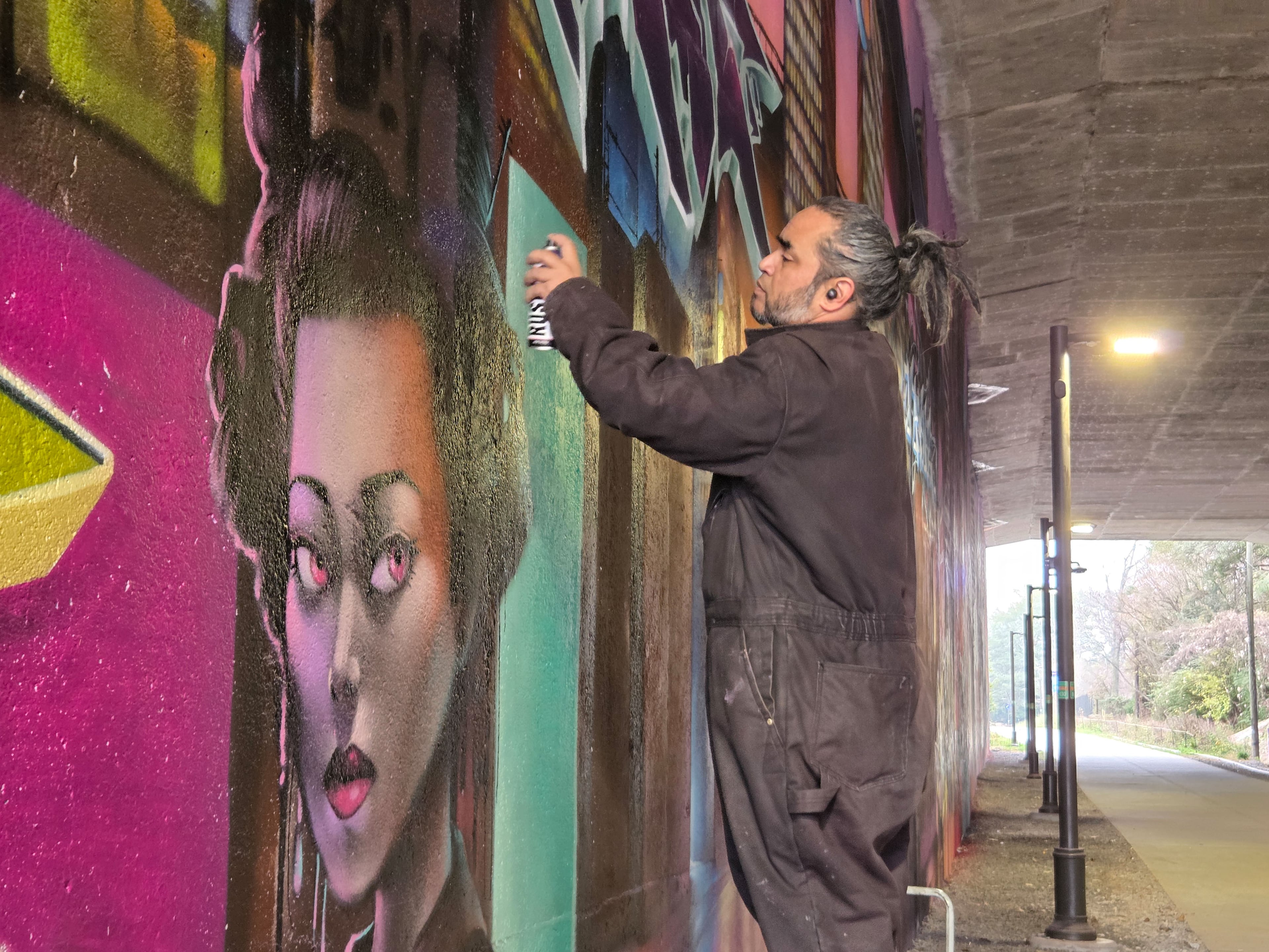 Mr. Totem works on a mural in progress along the Northeast Beltline trail.
(Arthur Rudick)