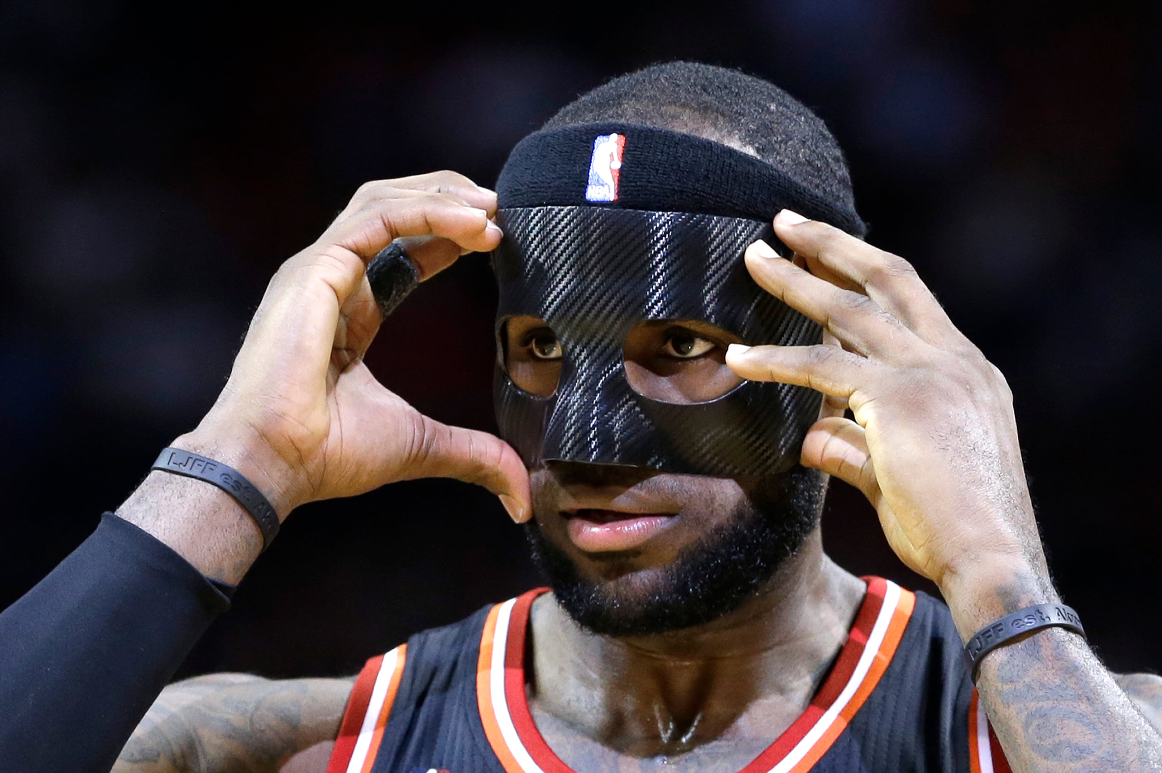 LeBron James (6) adjusts his mask during an NBA basketball game against the New York Knicks in Miami, Thursday, Feb. 27, 2014.