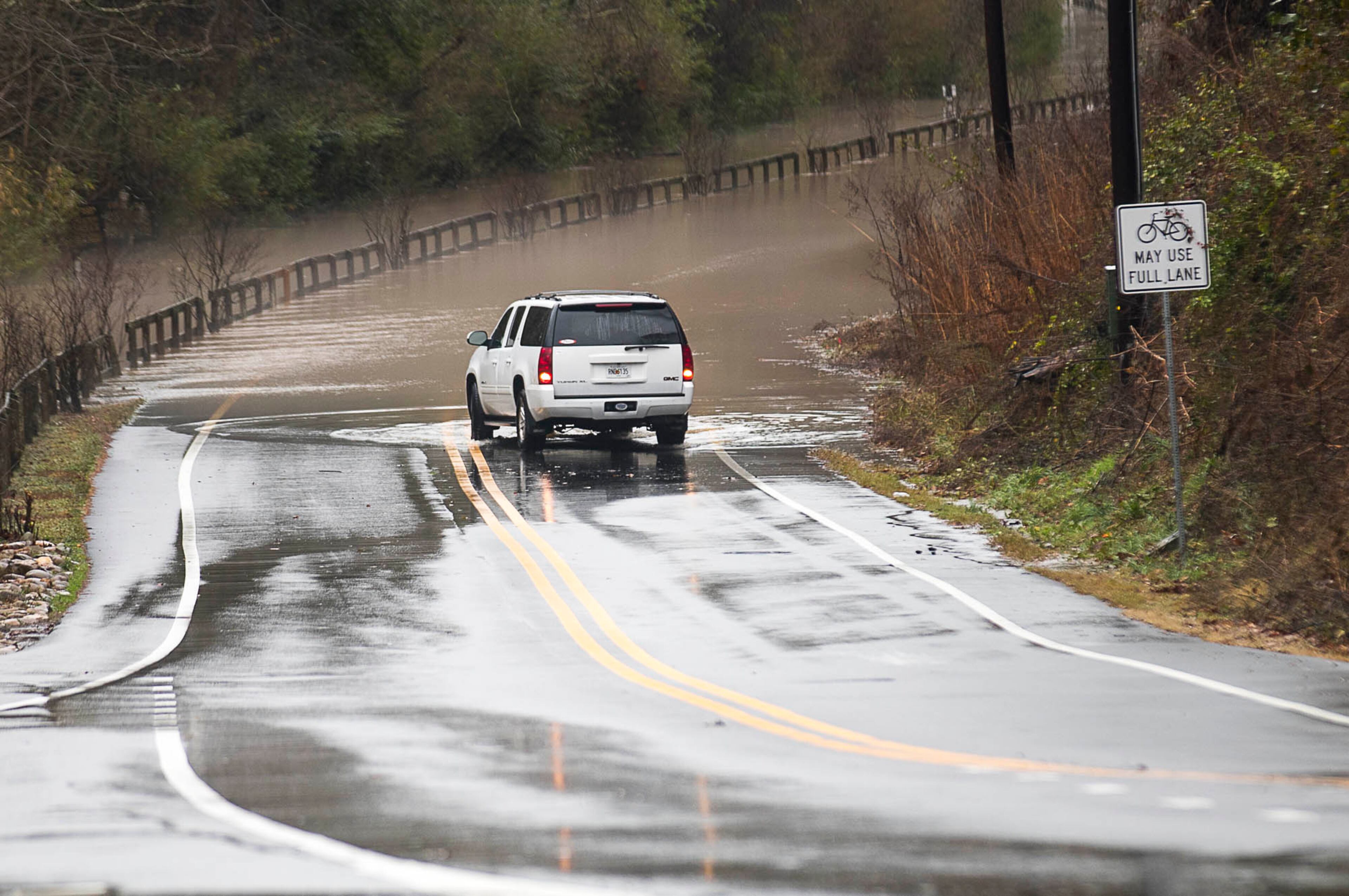 12/28/2018 -- Roswell, Georgia -- A car reverses from flood waters along Azalea Drive in Roswell, Friday, December 28, 2018. Azalea Drive, between Wileo Road and Riverside Drive, was closed off to cars Friday after persistent rain fell the night before causing major flooding along the Chattahoochee River. (ALYSSA POINTER/ALYSSA.POINTER@AJC.COM)