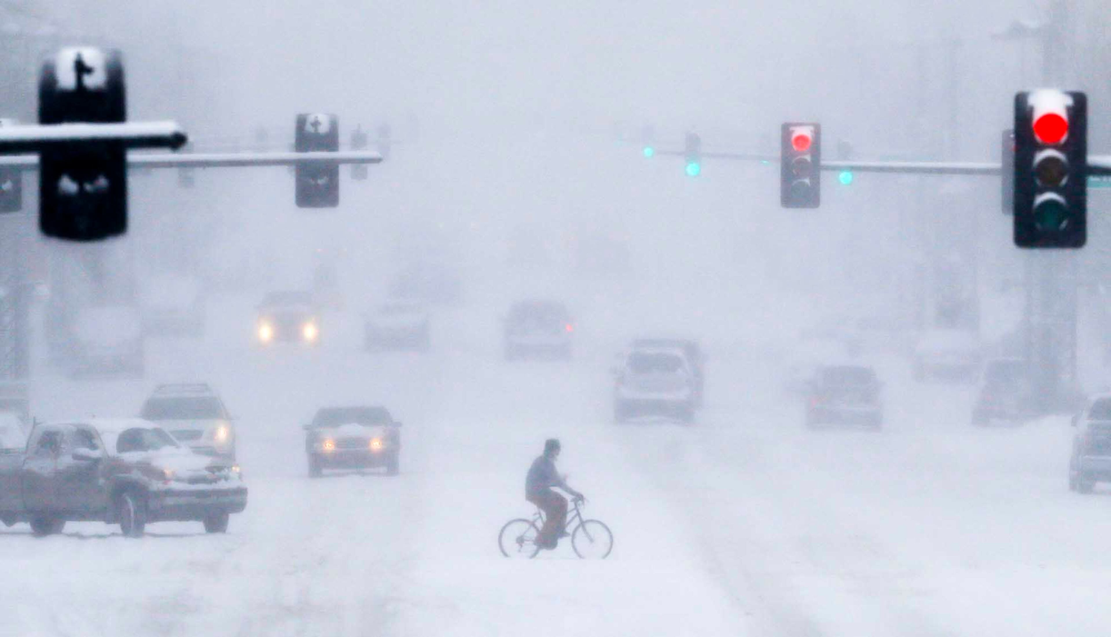 A bicyclist crosses Douglas Avenue in downtown Wichita, Kan., during a heavy snowstorm on Tuesday, Feb. 4, 2014. South-central Kansas is expecting up to seven inches of snow as a winter storm passes through.