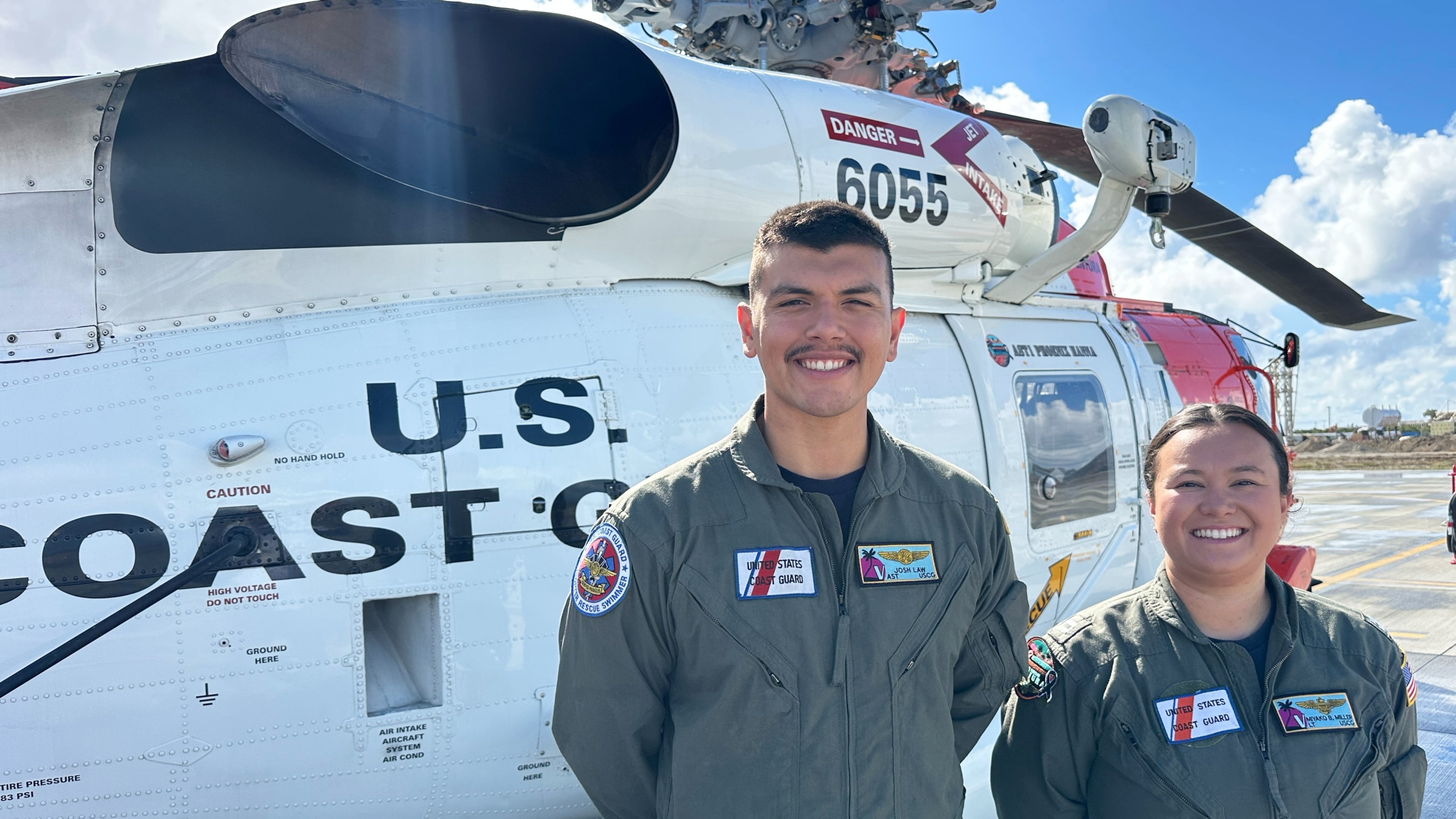 This photo made with a smartphone shows U.S. Coast Guard officer Josh Law, left, and lieutenant Miyako Miller standing in front of a rescue helicopter at the U.S. Coast Guard Air Station in Ventura, Calif., Thursday, Oct. 22, 2026. (AP Photo/Eugene Garcia)