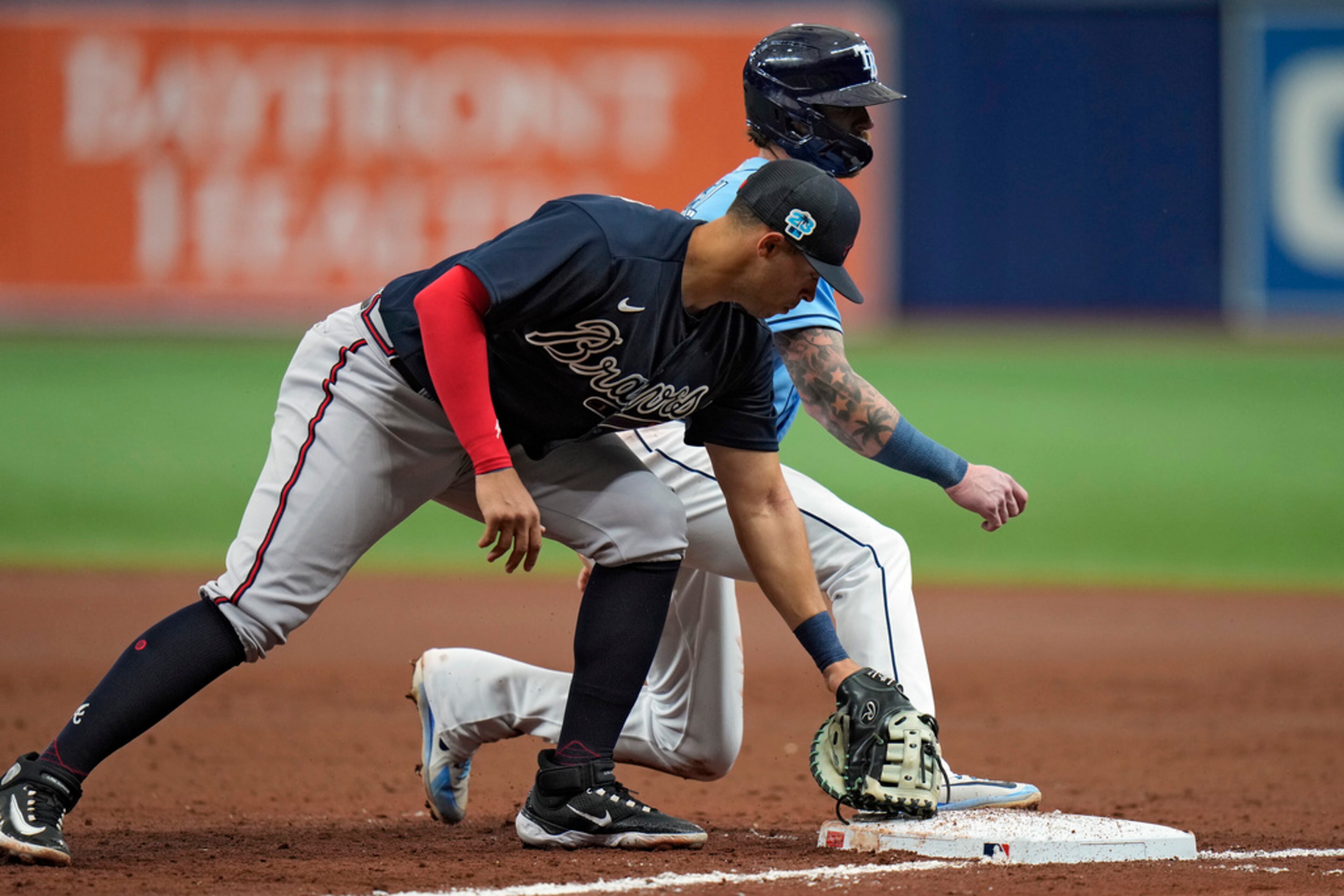 Tampa Bay Rays' Ben Gamel, background, is safe at first after the tag by Atlanta Braves first baseman Joe Dunand on a pickoff attempt is late during the third inning of a spring training baseball game Friday, March 10, 2023, in St. Petersburg, Fla. (AP Photo/Chris O'Meara)