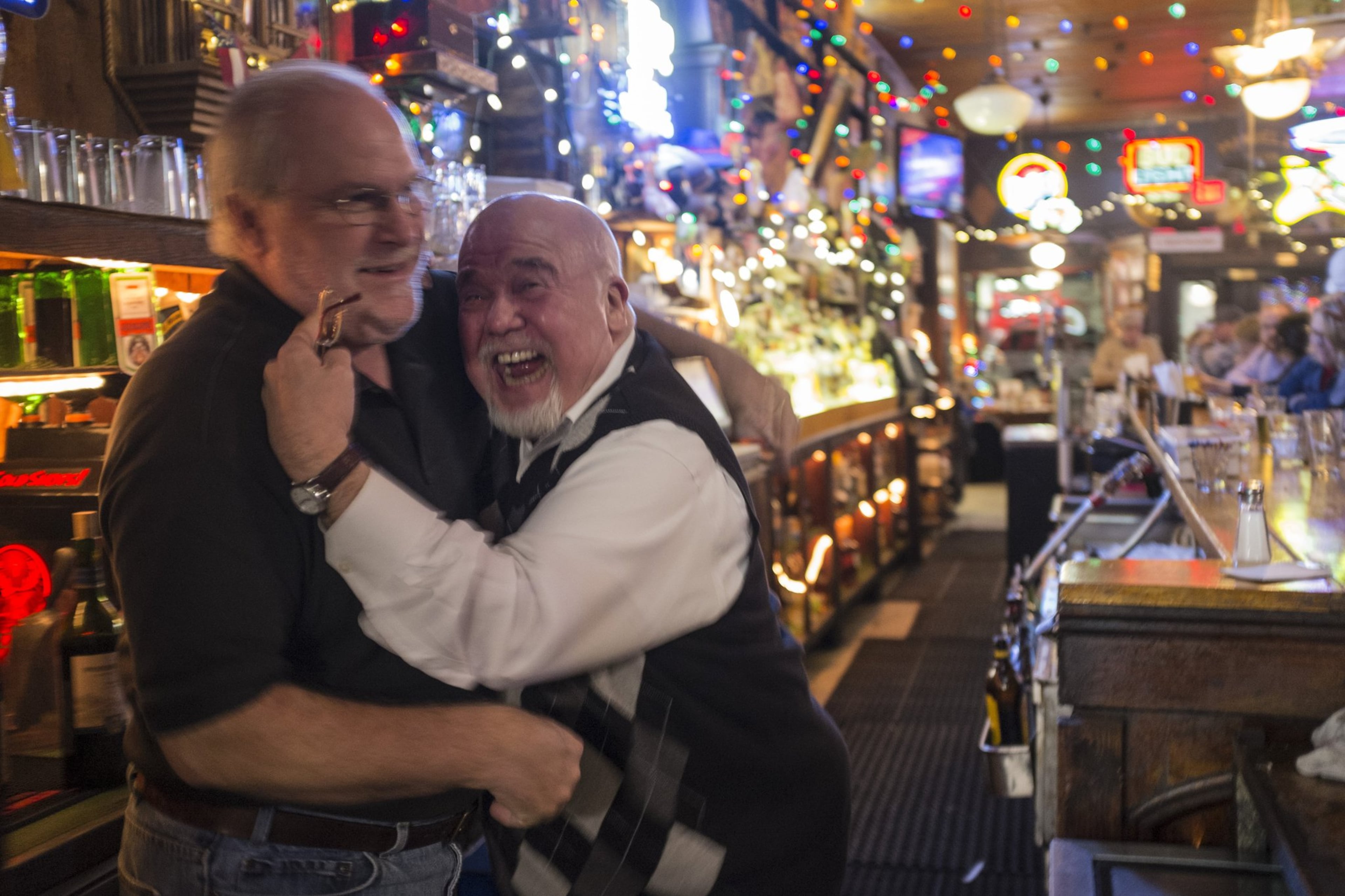 Manuel’s Tavern bartender Bobby Agee (left) gets a raucous hug from Atlanta politico Tom Houck. (Ben Gray/AJC)