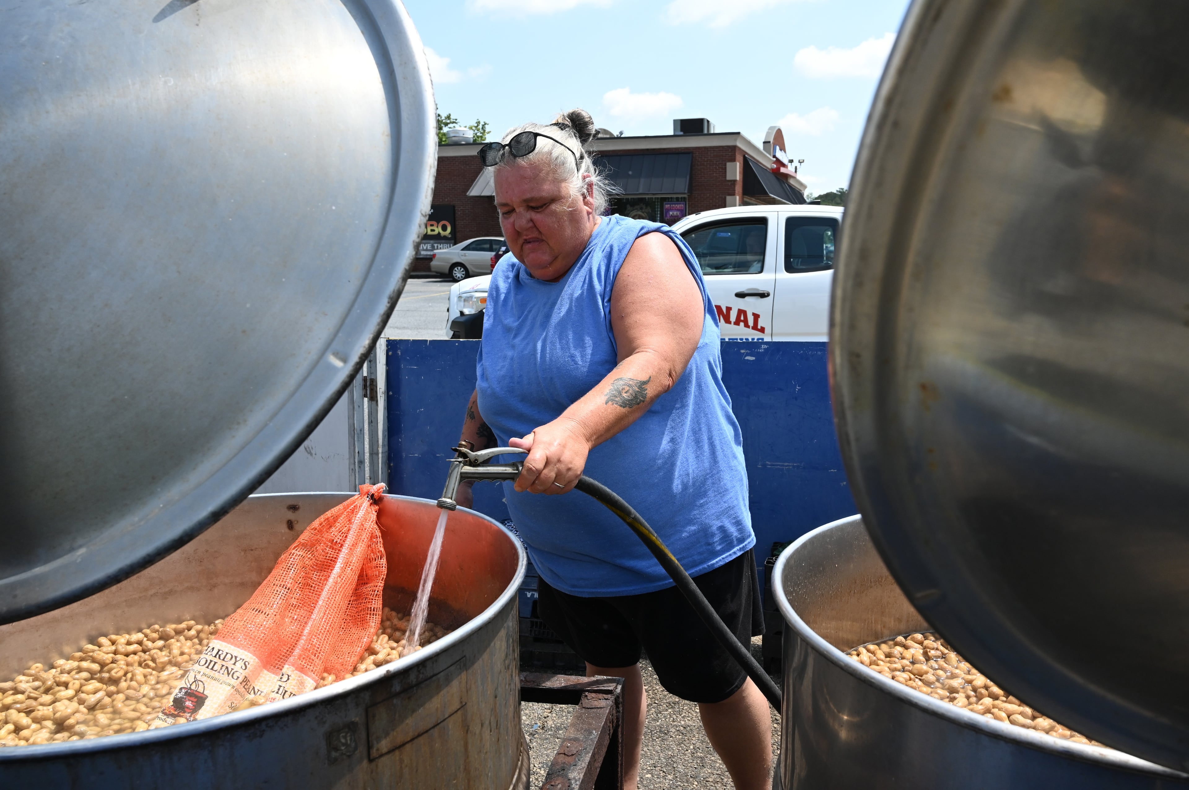 Timmi Moore adds some water as she warms up peanuts in a steam kettle at one of Hardy Farms’ roadside stands in Warner Robins. (Hyosub Shin/AJC)