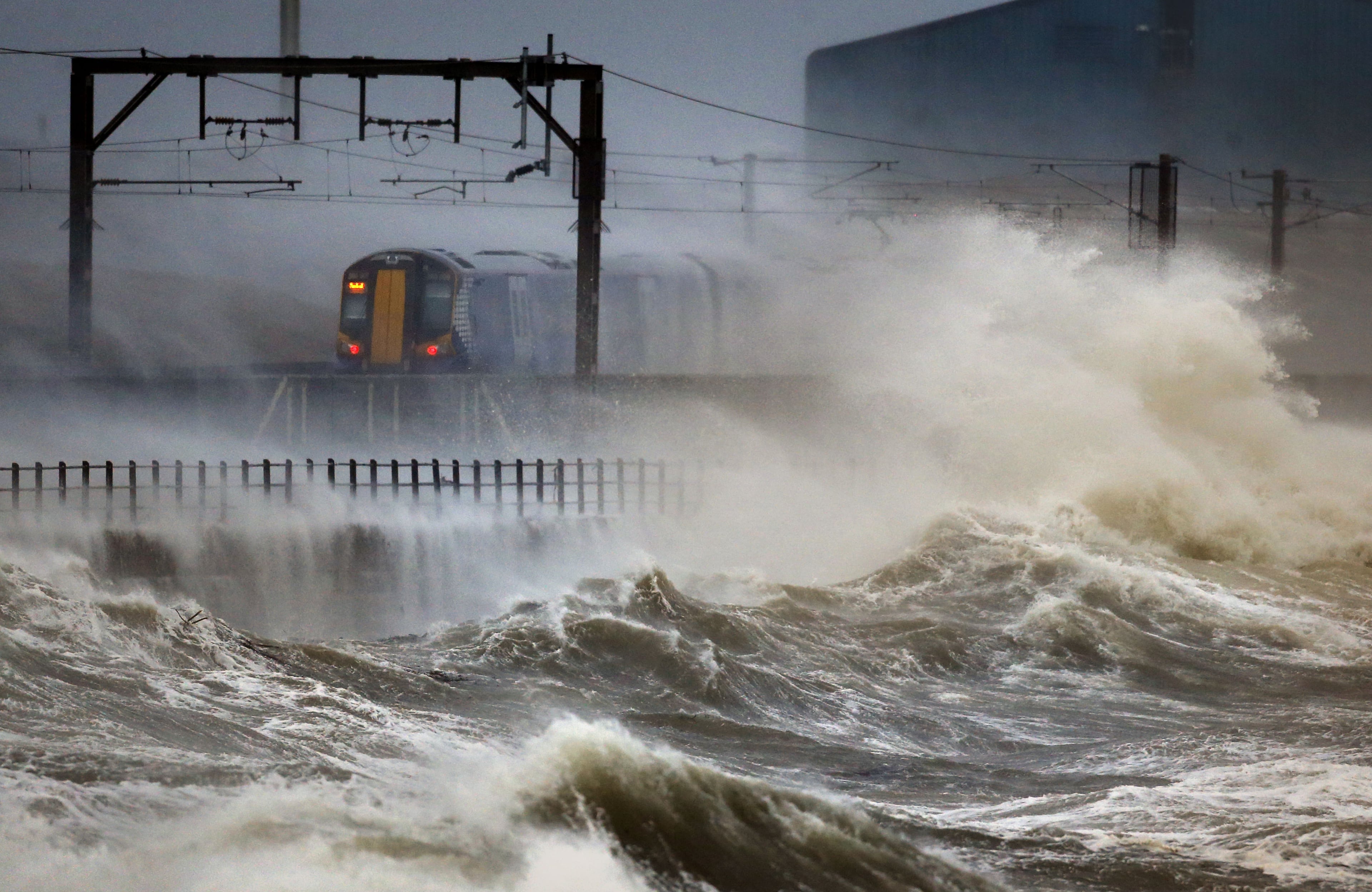 A train passes along the coast at Saltcoats in Scotland, Friday, Jan. 2014, as Britain is braced for the worst as a combination of high tides, heavy rains and strong winds are expected to bring yet more severe flooding to many parts of the country. The storm follows severe weather in early December and over Christmas. (AP Photo/PA, Danny Lawson)