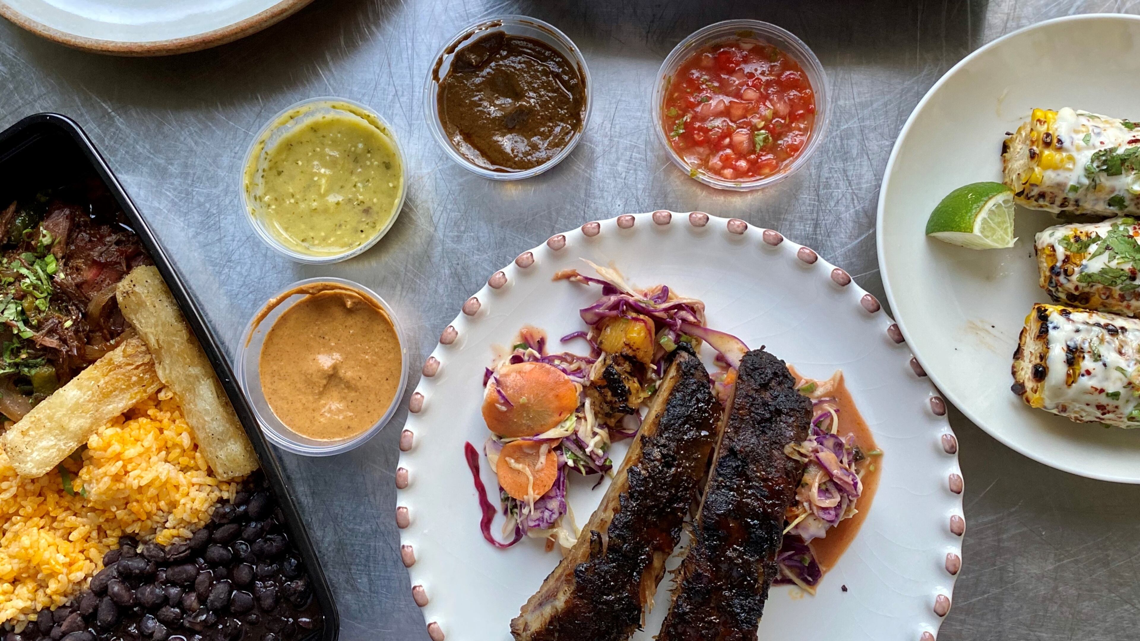 Takeout from Bar Mercado includes (clockwise from upper left): grilled shrimp, with crispy okra; grilled Peruvian-spiced chicken, with black beans, rice and Salvadoran slaw; Mexican street corn; glazed ribs, with pineapple slaw; short-rib ropa vieja, with beans, rice and yuca fries. Wendell Brock for The Atlanta Journal-Constitution