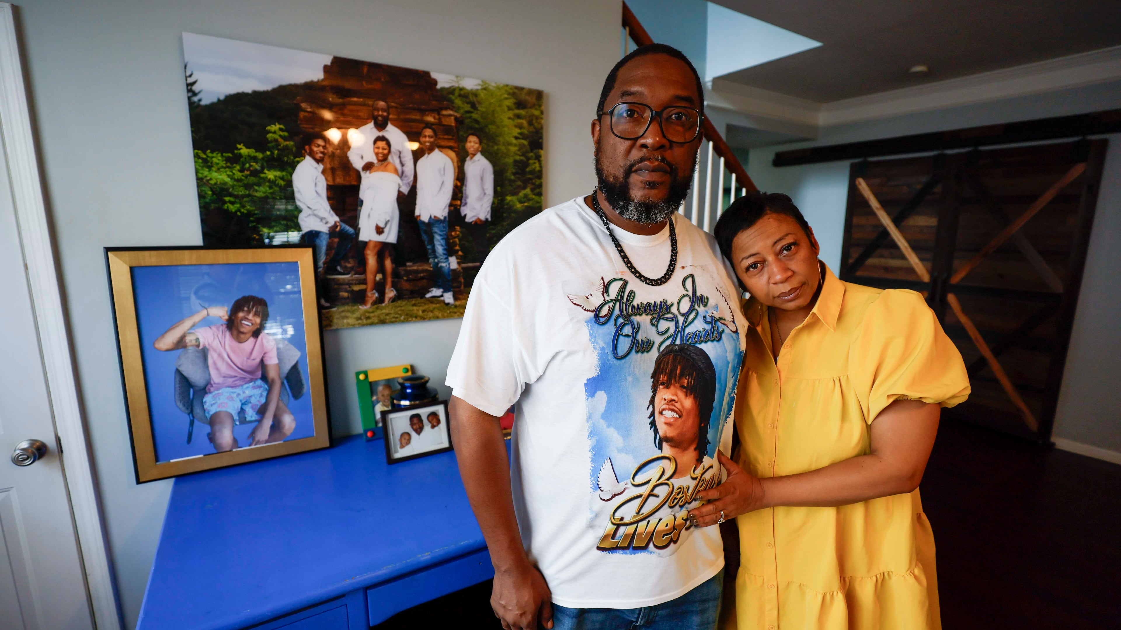 Ramonne and Terrica Thomas stand in the living room of their Mableton home, surrounded by images of their son, Boston Thomas, who was killed in May 2024 when a Cobb County police officer used a PIT maneuver to end a high-speed chase. The parents have filed a lawsuit against the county. (Miguel Martinez/AJC)