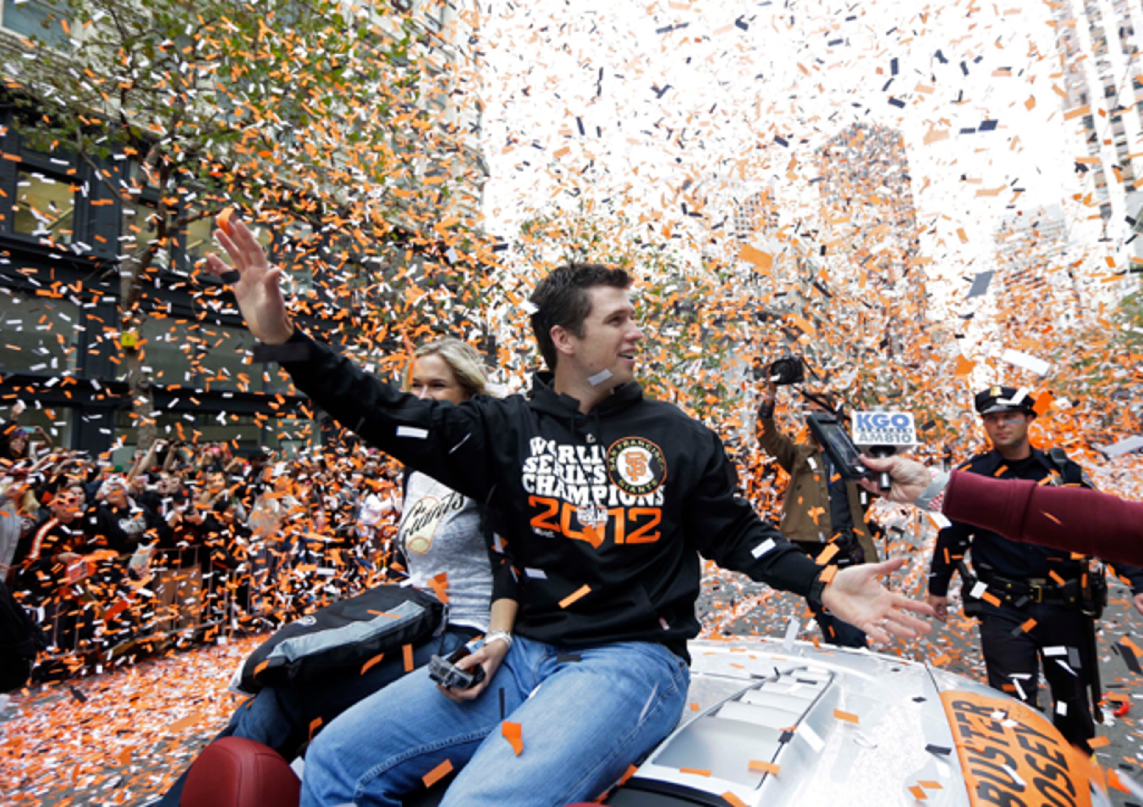 San Francisco Giants catcher Buster Posey waves and is showered with confetti during the Giants' baesball World Series victory parade on Market Street in San Francisco, Wednesday, Oct. 31, 2012. (AP Photo/Marcio J. Sanchez)