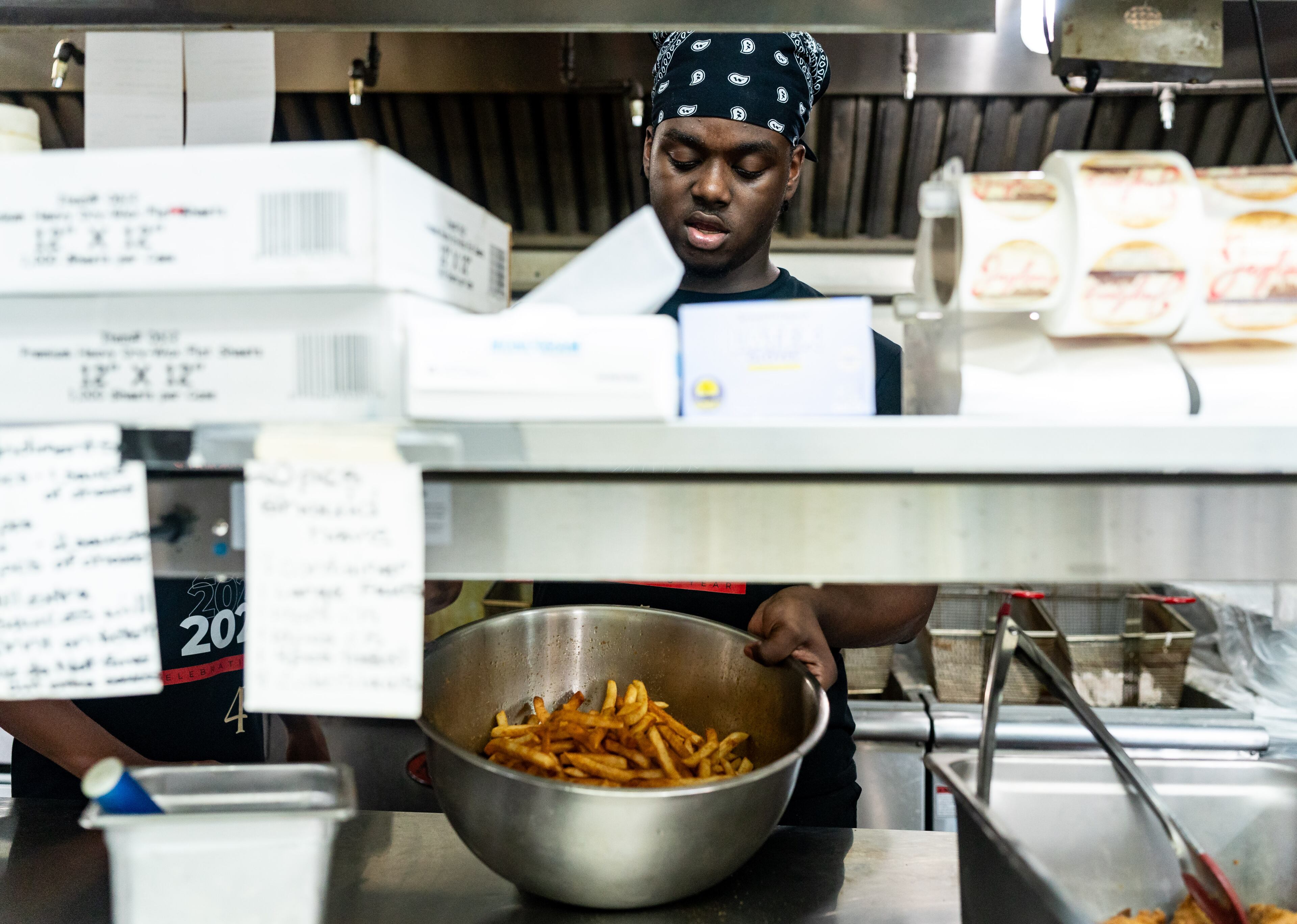 Manager Qú Jones tosses fries in seasoning at Jaybee's Tenders in Decatur, GA on Thursday, July 25, 2024. (Seeger Gray / AJC)