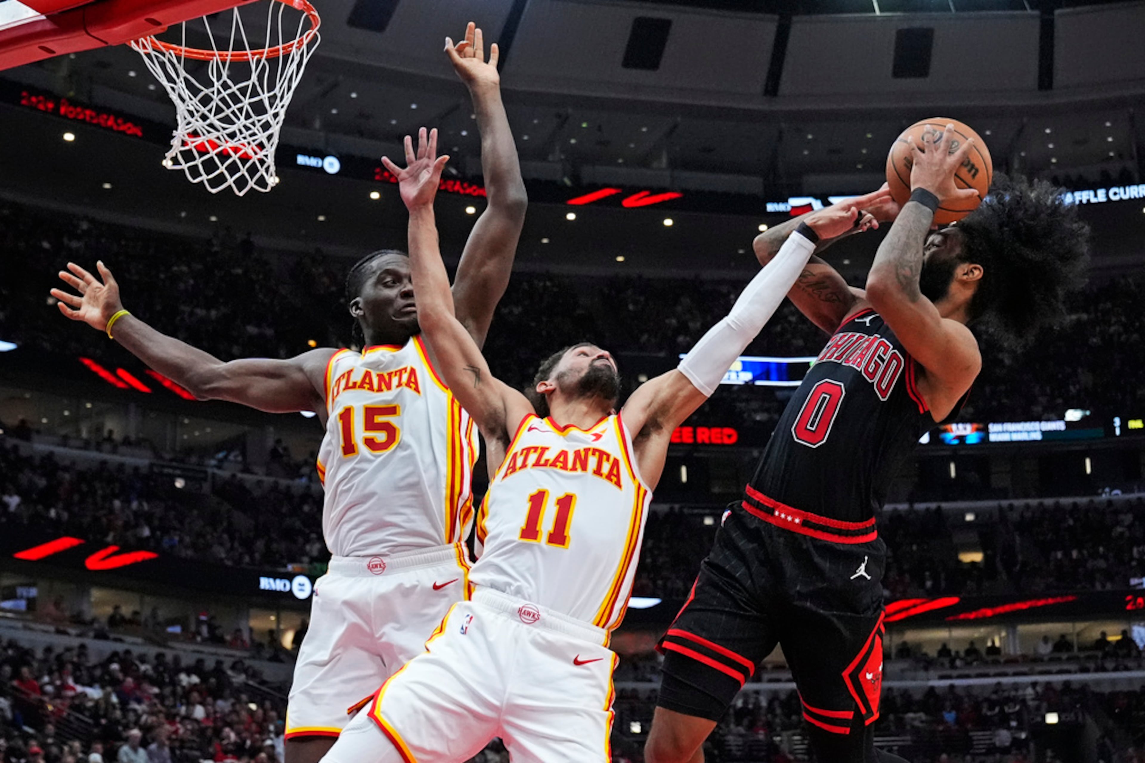 Chicago Bulls guard Coby White, right, shoots against Atlanta Hawks guard Trae Young, center, and center Clint Capela during the second half of an NBA basketball play-in tournament game in Chicago, Wednesday, April 17, 2024. The Bulls won 131-116. (AP Photo/Nam Y. Huh)