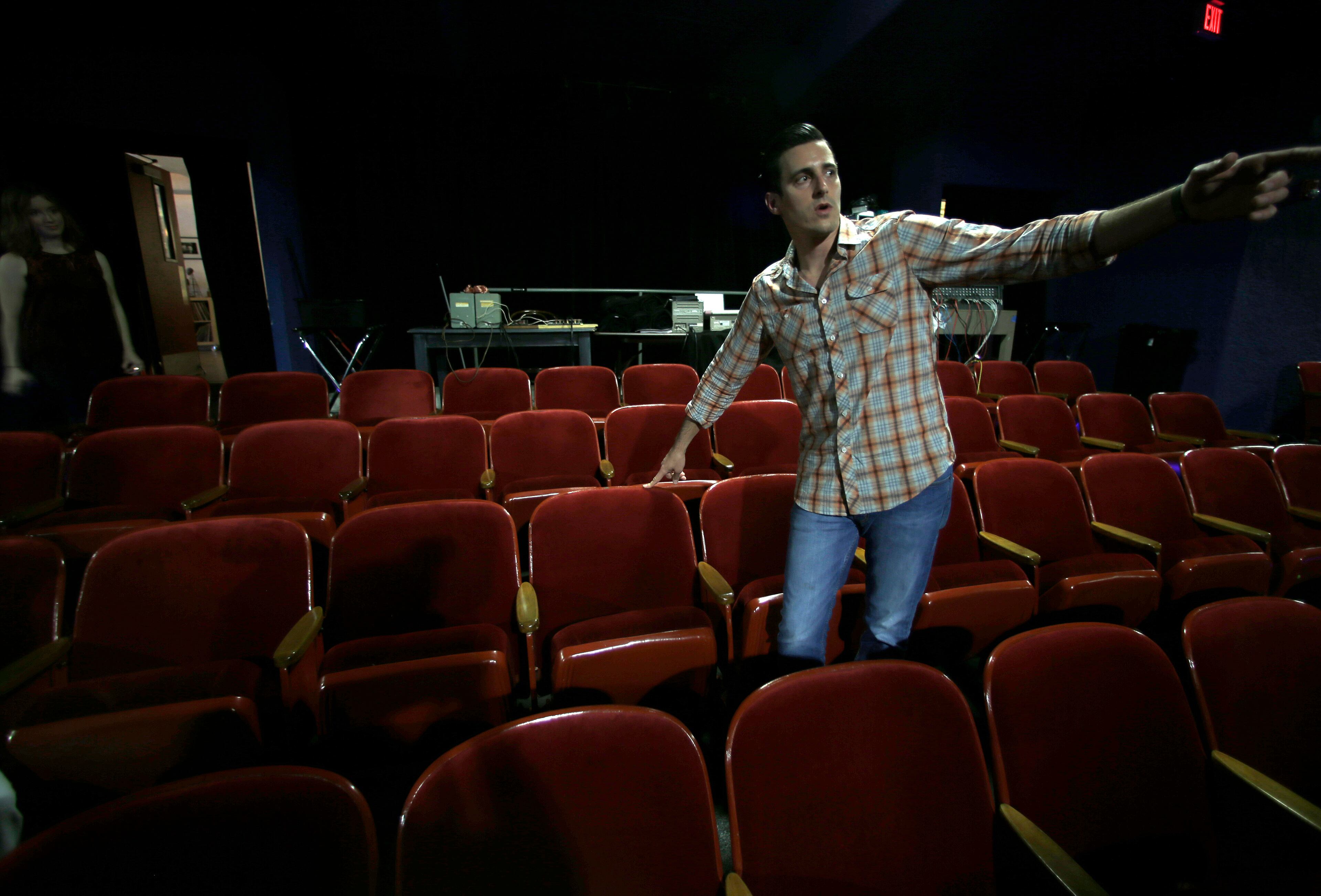 In this photo made in 2013, Eric Steele, who operates the Texas Theater, points simultaneously to the seat where Lee Harvey Oswald was sitting and the door where Dallas Police entered the theater to arrest him in the Oak Cliff section of Dallas. Lee Harvey Oswald was arrested at the theater Nov. 22, 1963, after the assassination of President John F. Kennedy. Oswald moved a few seats to the left before police were able to take him into custody. (AP Photo/LM Otero)