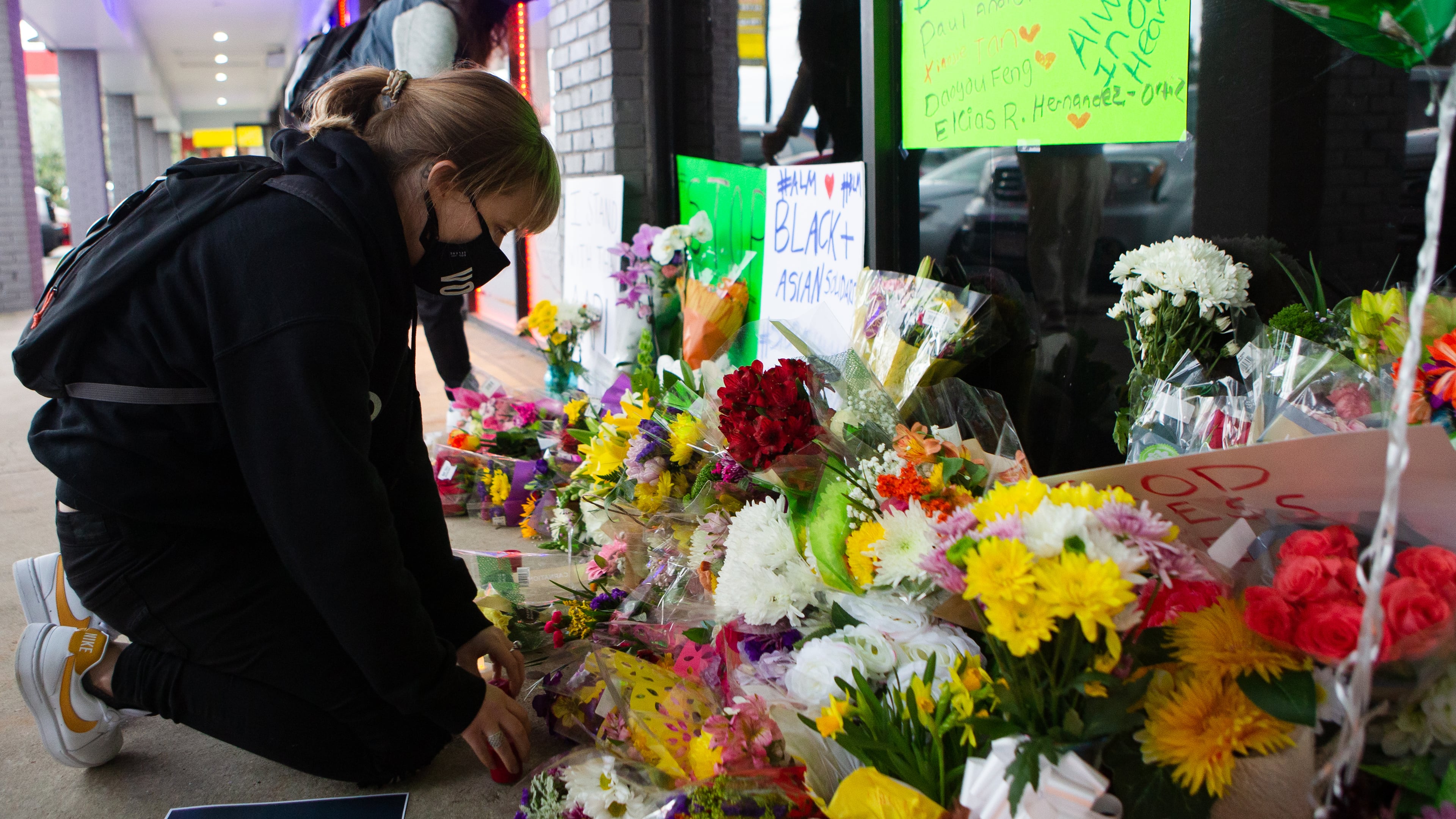Shelby Swan rearranges flowers at a memorial during a candlelight vigil to honor the lives of those killed at Youngs Asian Massage in March.