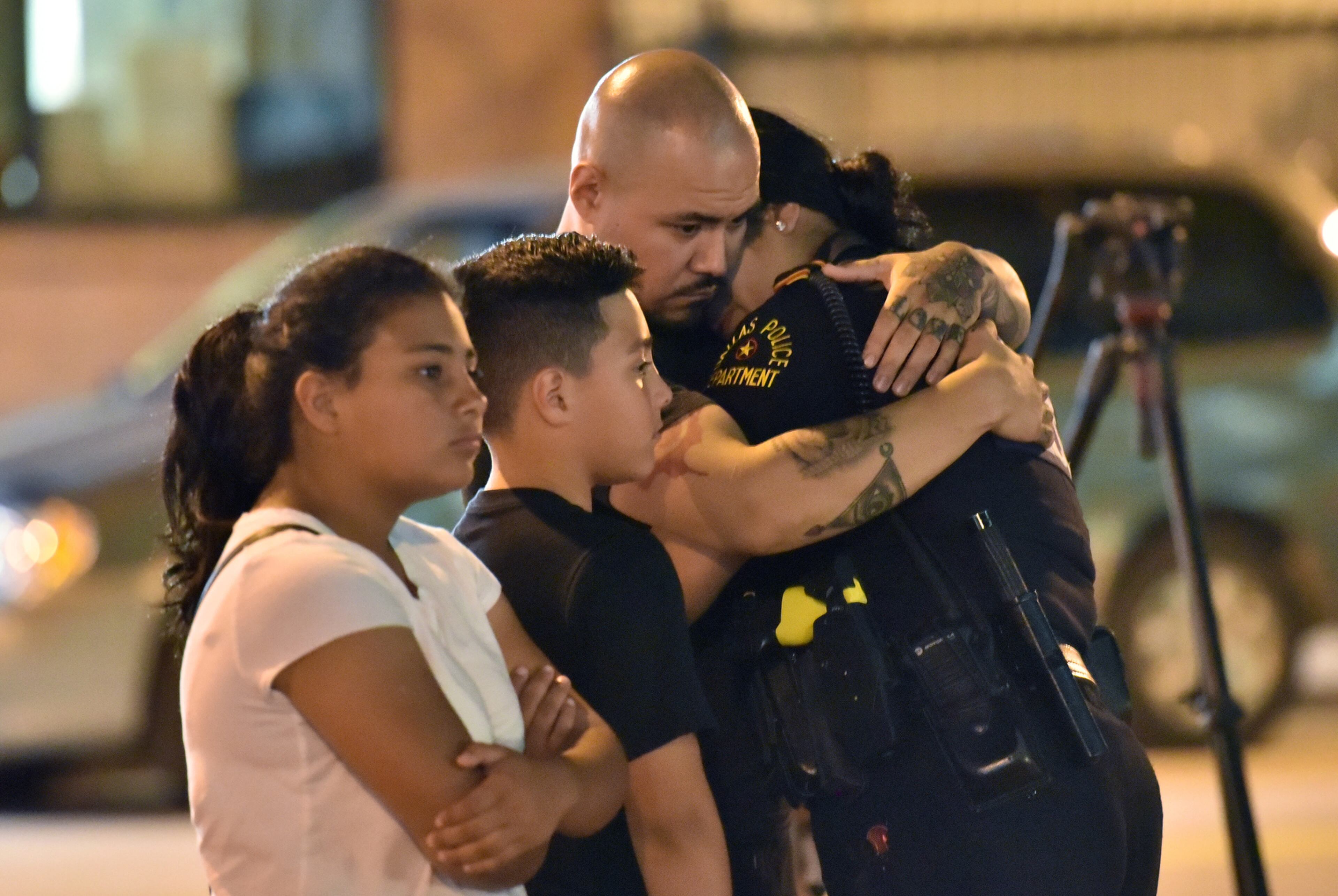 July 8, 2016 Dallas, Texas - Fermin Betancourt comforts his girlfriend Dallas police officer Yuridia Morales (right) near police cars decorated as a public memorial in front of Dallas police headquarters Friday night, July 8, 2016. HYOSUB SHIN / HSHIN@AJC.COM