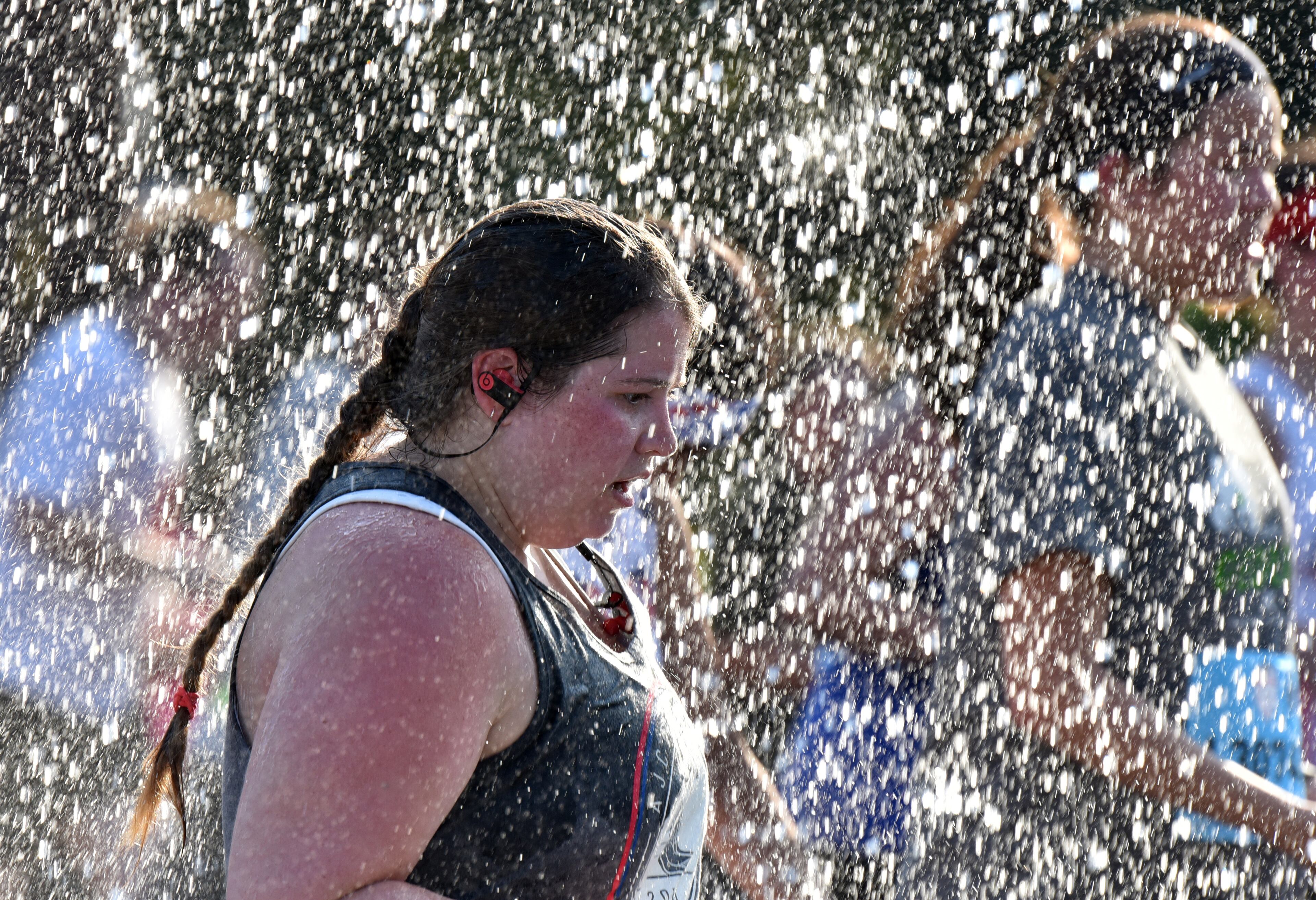July 4, 2018 Atlanta - Runners cool off in a shower of water that refreshed them just before they approach Cardiac Hill during the AJC Peachtree Road Race on Wednesday, July 4, 2018. HYOSUB SHIN / HSHIN@AJC.COM
