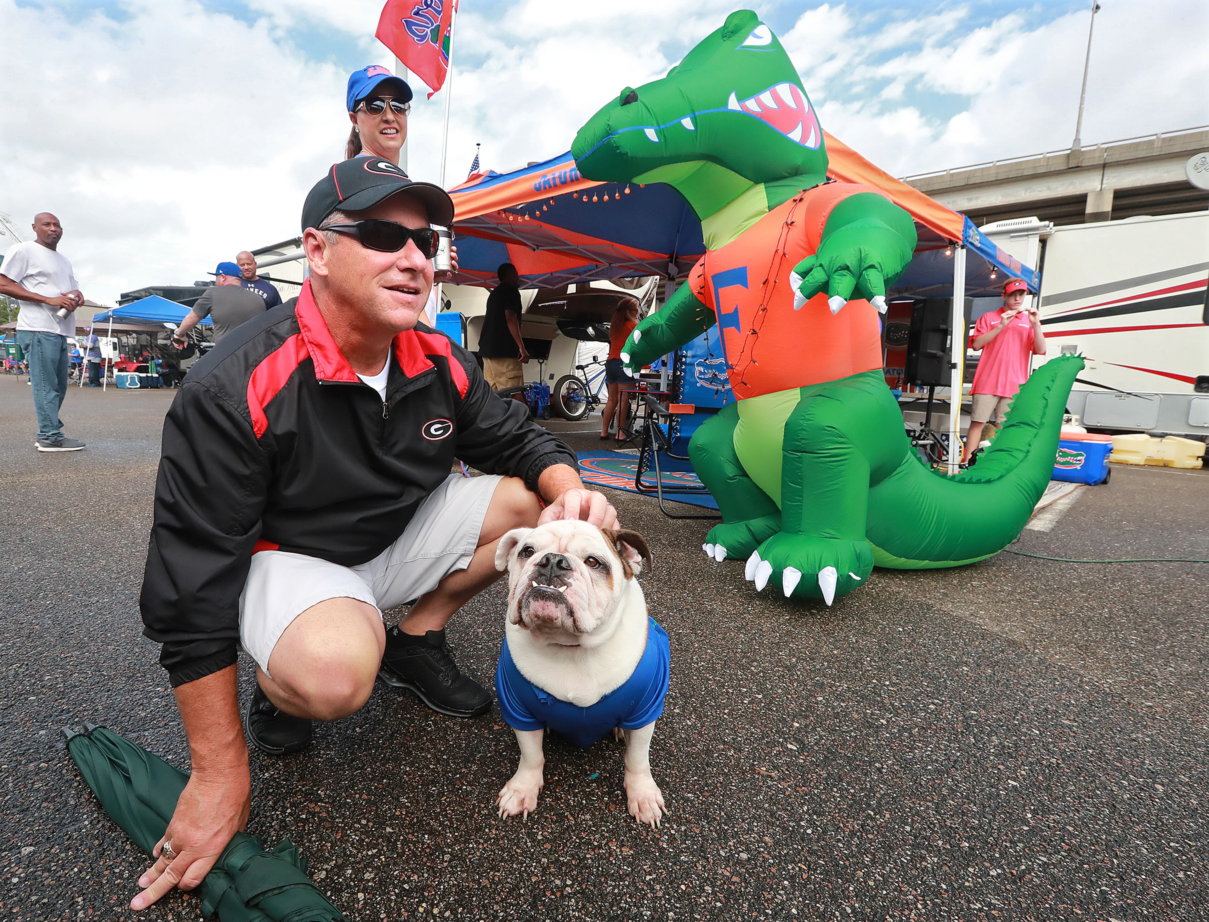 A Florida Bulldog? Georgia fan Brian McGugan of Grayson stops to have his picture taken with Kerrie Sessions' Florida Bulldog named Meatloaf while tailgating in the RV Park outside TIAA Bank Field Friday. (Curtis Compton/ccompton@ajc.com)