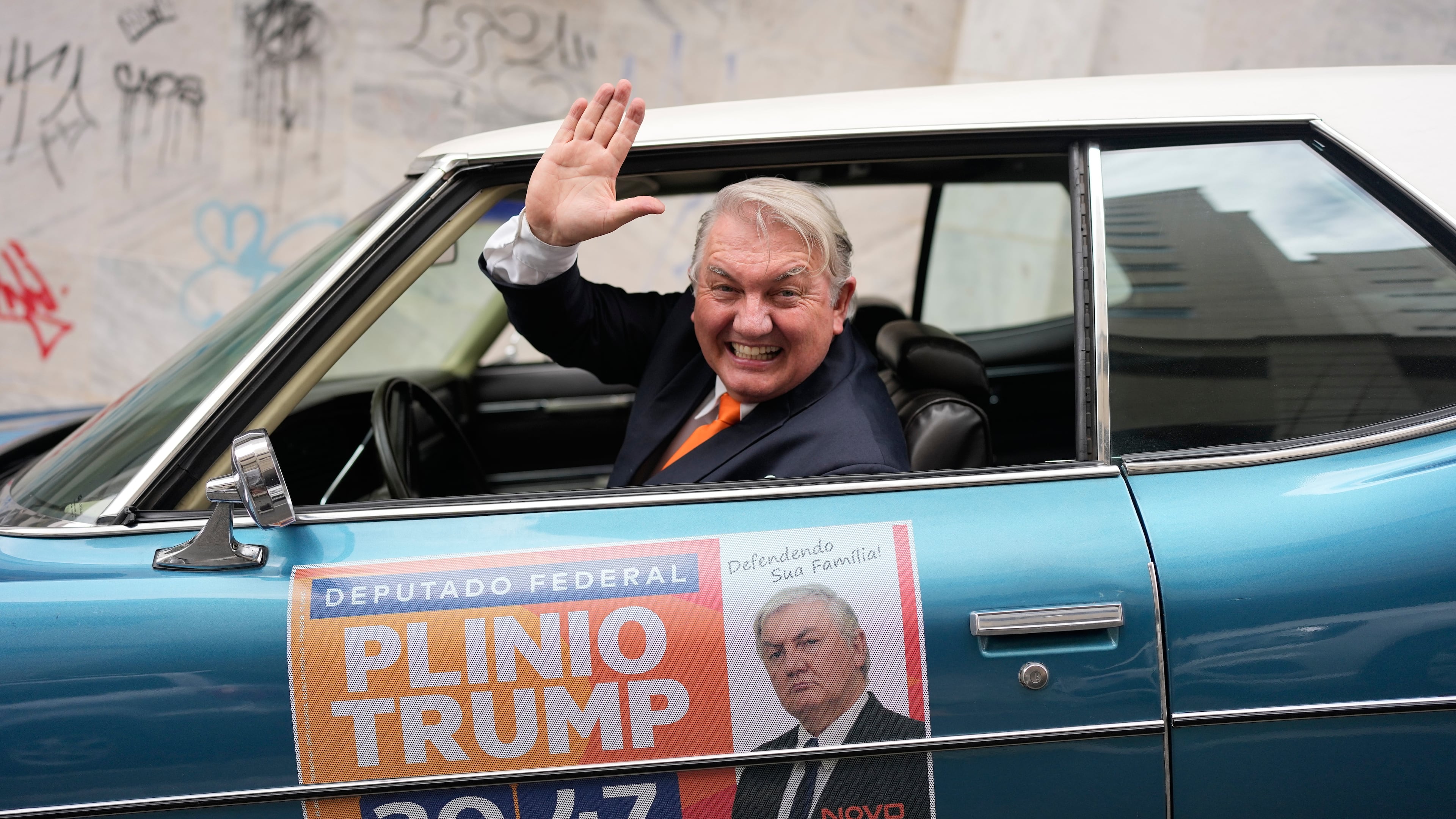 Plinio Vicentin Jr., who is running for federal lawmaker as "Plinio Trump," with the Novo Party representing Minas Gerais state, campaigns from his car ahead of the general election in Juiz de Fora, Minas Gerais state, Brazil, Monday, Sept. 28, 2026. (AP Photo/Silvia Izquierdo)